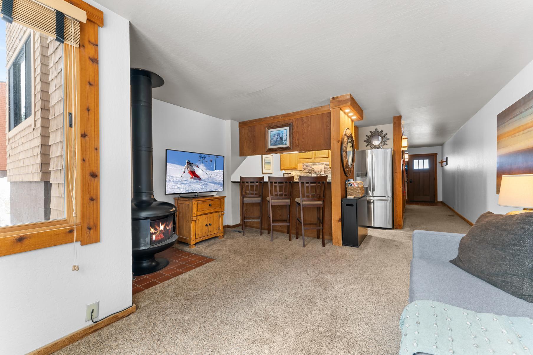 Cozy living area in Truckee vacation rental with fireplace, TV, bar seating, and modern kitchen.