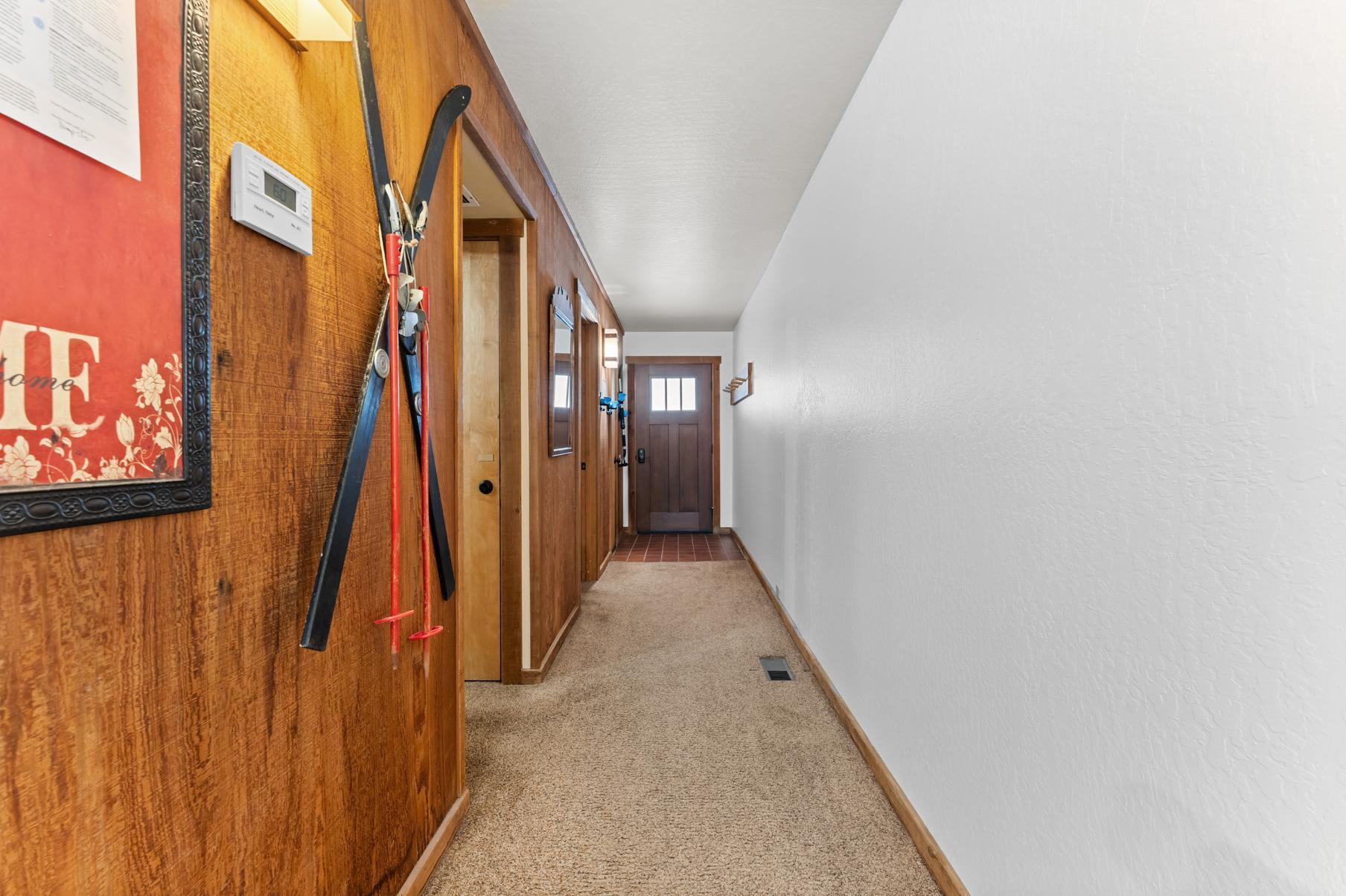 Hallway of a Truckee vacation rental with wooden decor, red skis on the wall, and a door leading outside.