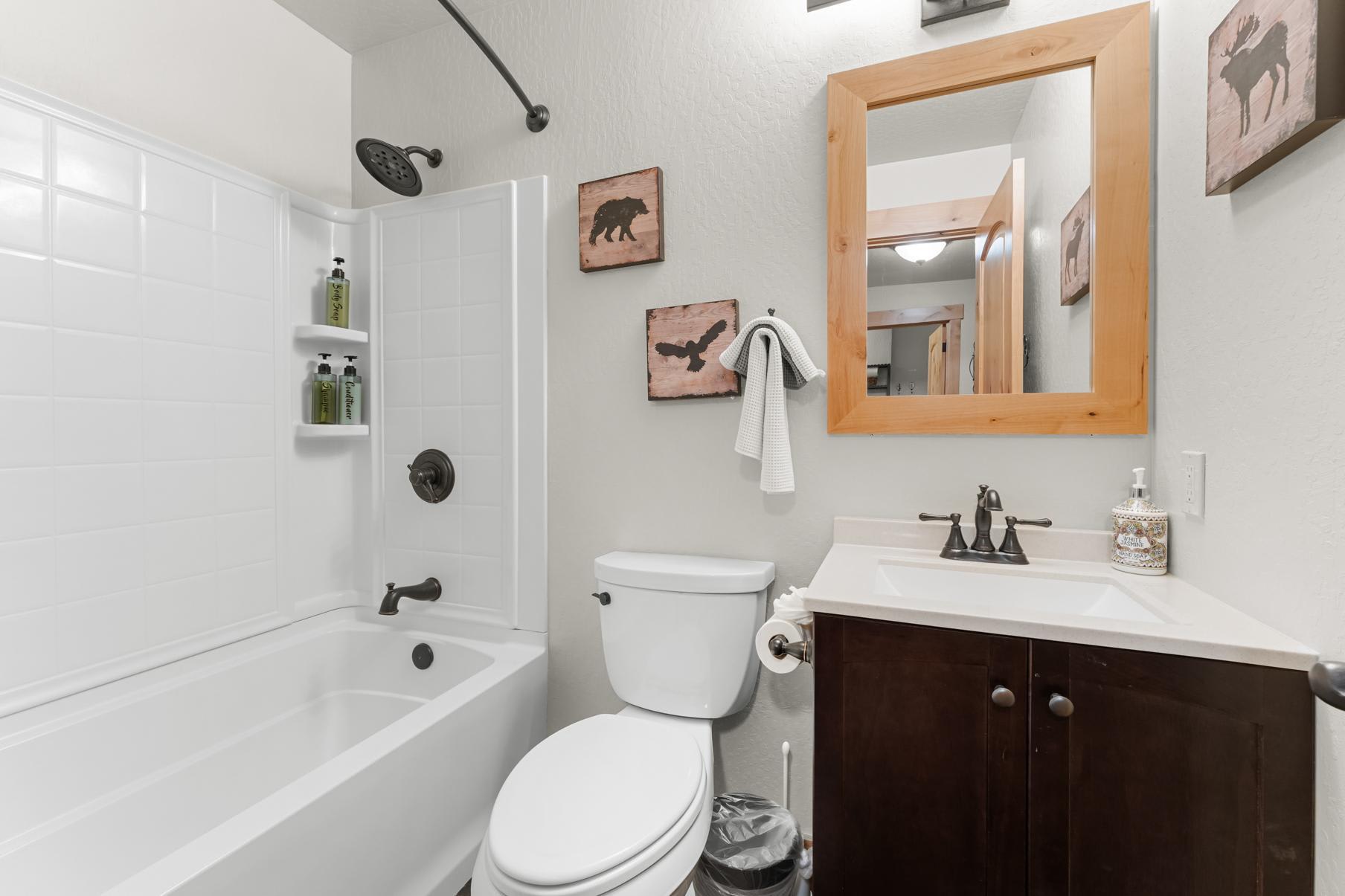 Bathroom in a Truckee vacation rental with a white tub, framed mirror, and wildlife-themed decor.