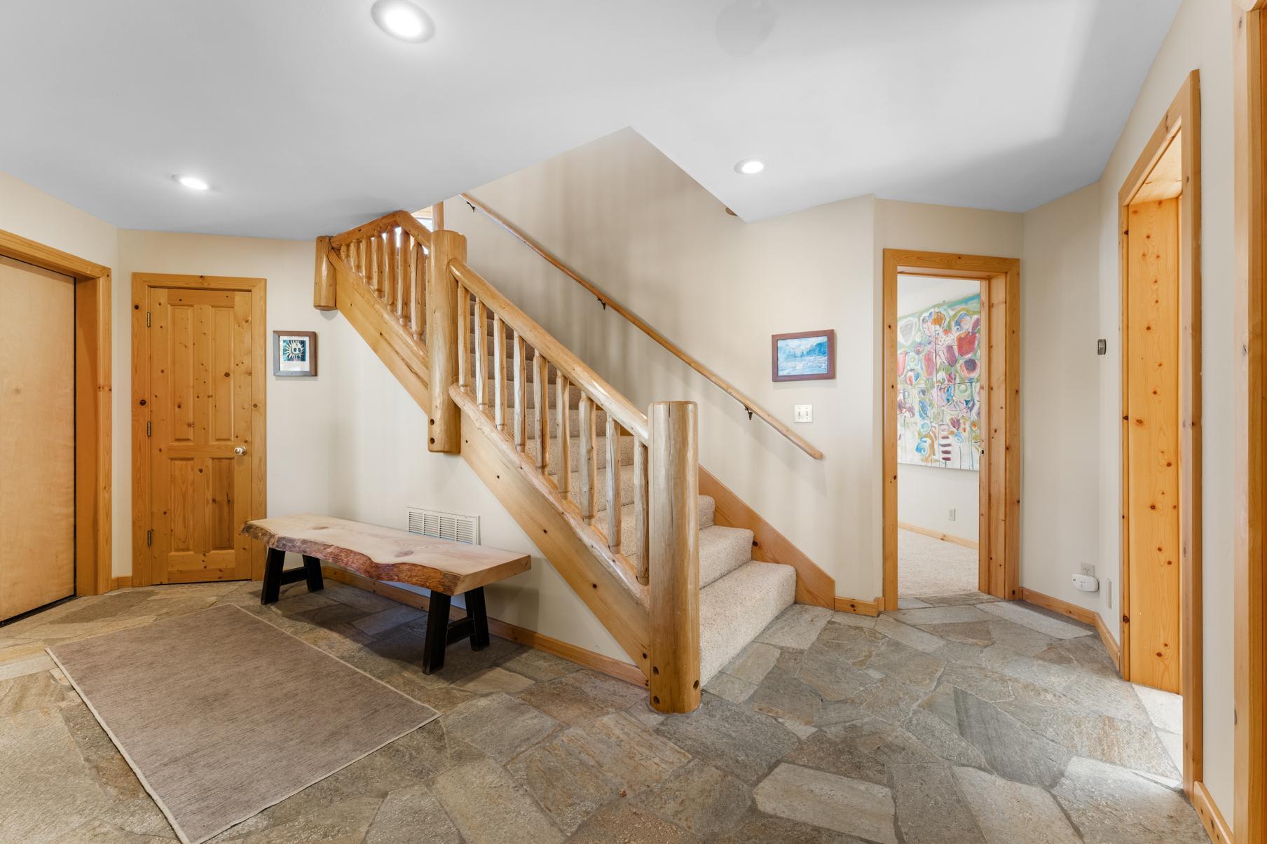 Wooden staircase and rustic hallway in a Truckee vacation rental, featuring stone flooring and cozy decor.