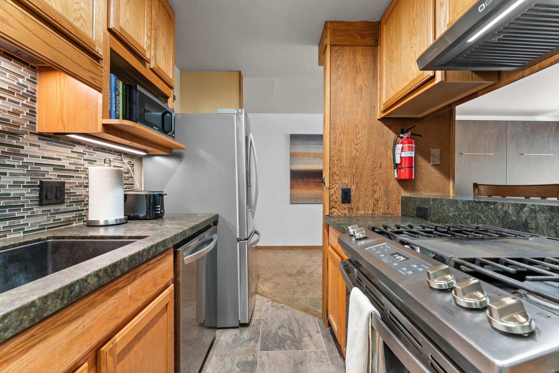 Modern kitchen in Truckee vacation rental with wooden cabinets, stainless steel appliances, and tiled backsplash.