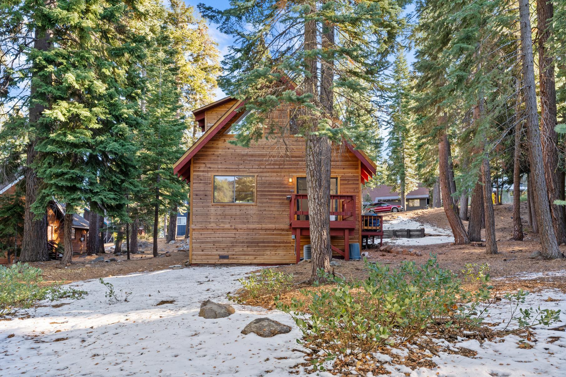 Cozy cabin-style vacation rental amidst tall trees and light snow in Tahoe Vista.