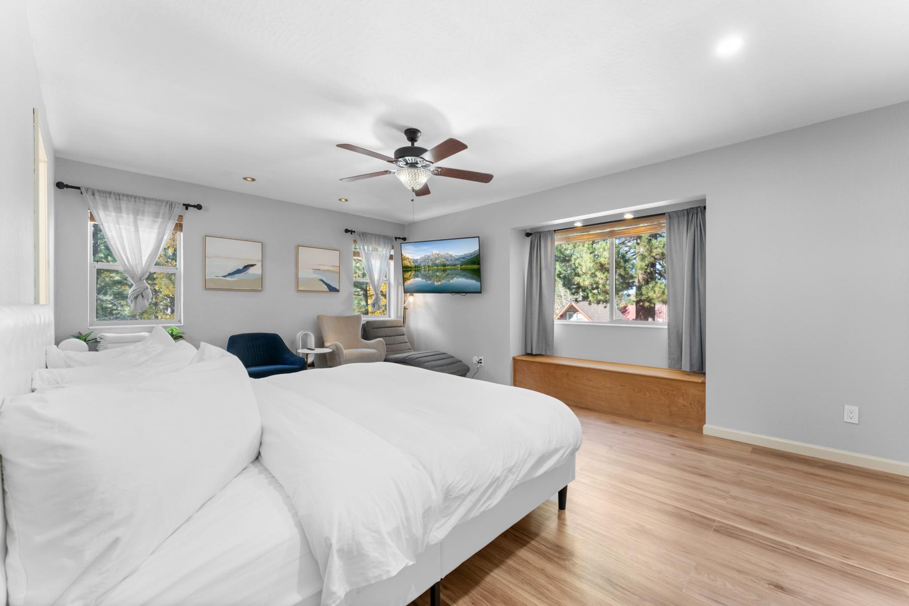 Spacious bedroom in a Truckee vacation rental with a king bed, armchairs, large windows, and scenic decor.