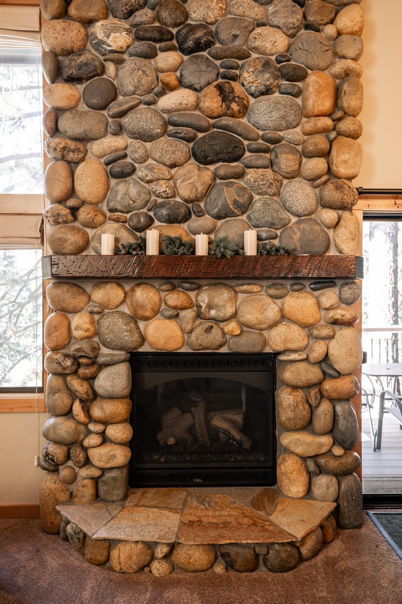 Stone fireplace in a Truckee vacation rental, with a rustic wooden mantle and candles on display.