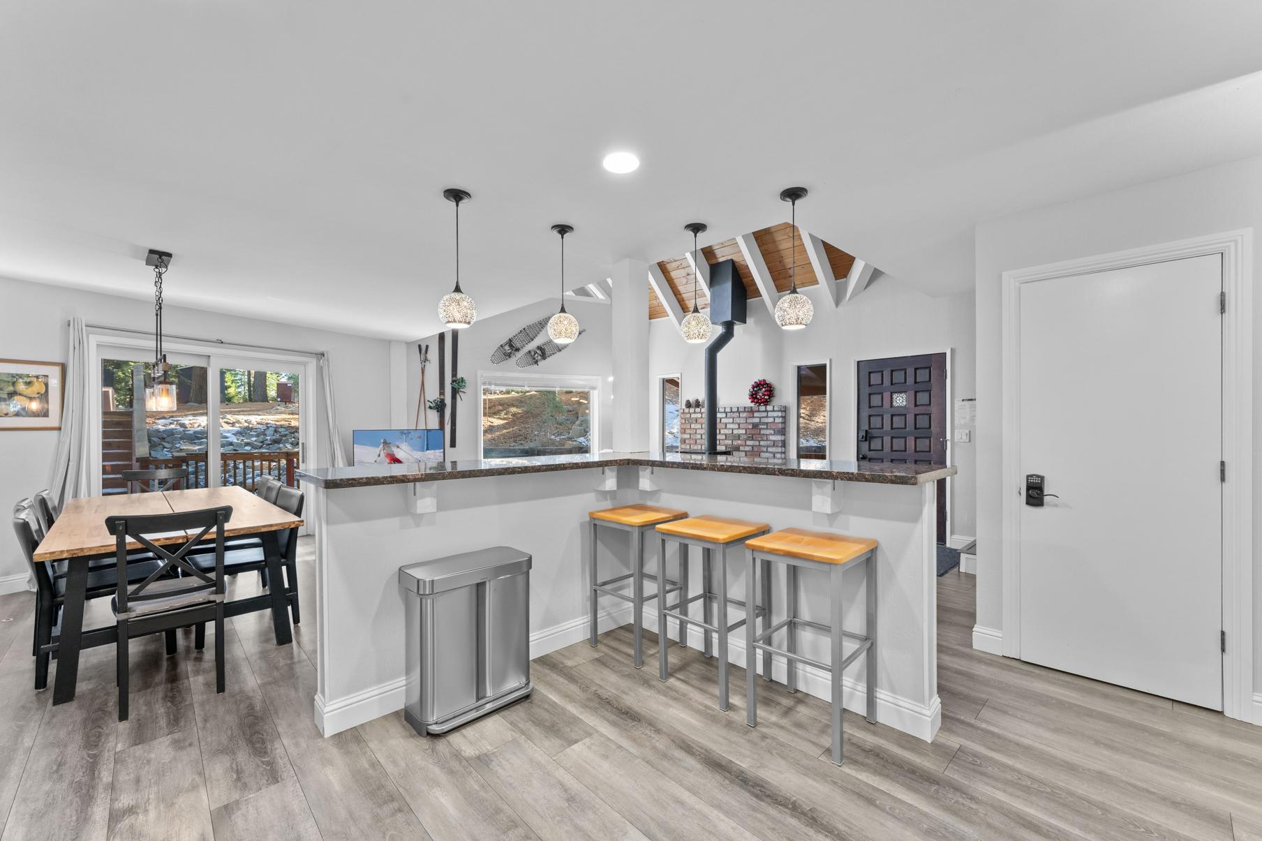 Modern kitchen and dining area in a Tahoe Vista vacation rental with wooden floors, bar stools, and a large window view.