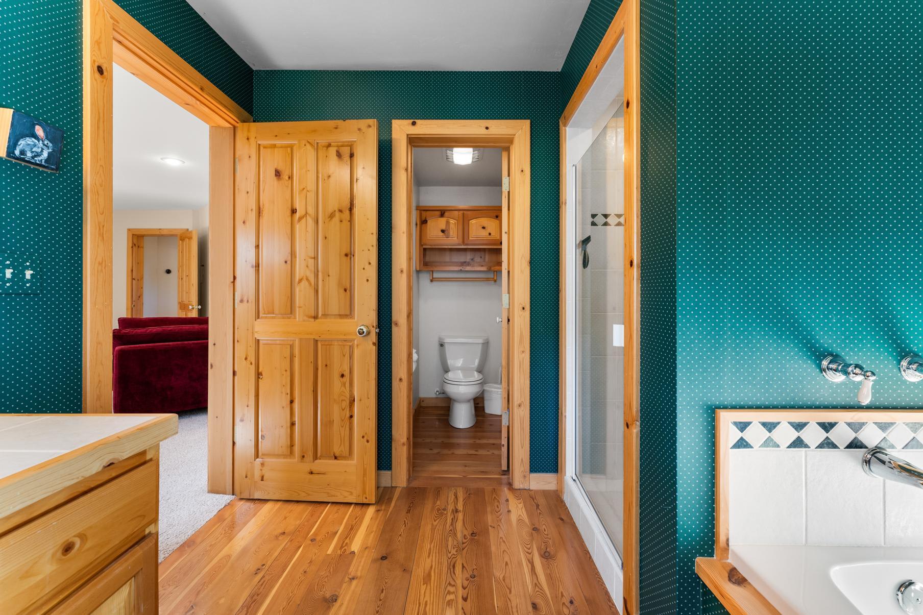 Bathroom in a Truckee vacation rental with wooden doors, green walls, and a view of the living area with a red sofa.