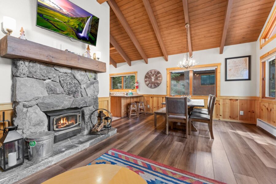 Cozy Truckee vacation rental with stone fireplace, wooden beams, dining set, and modern decor.