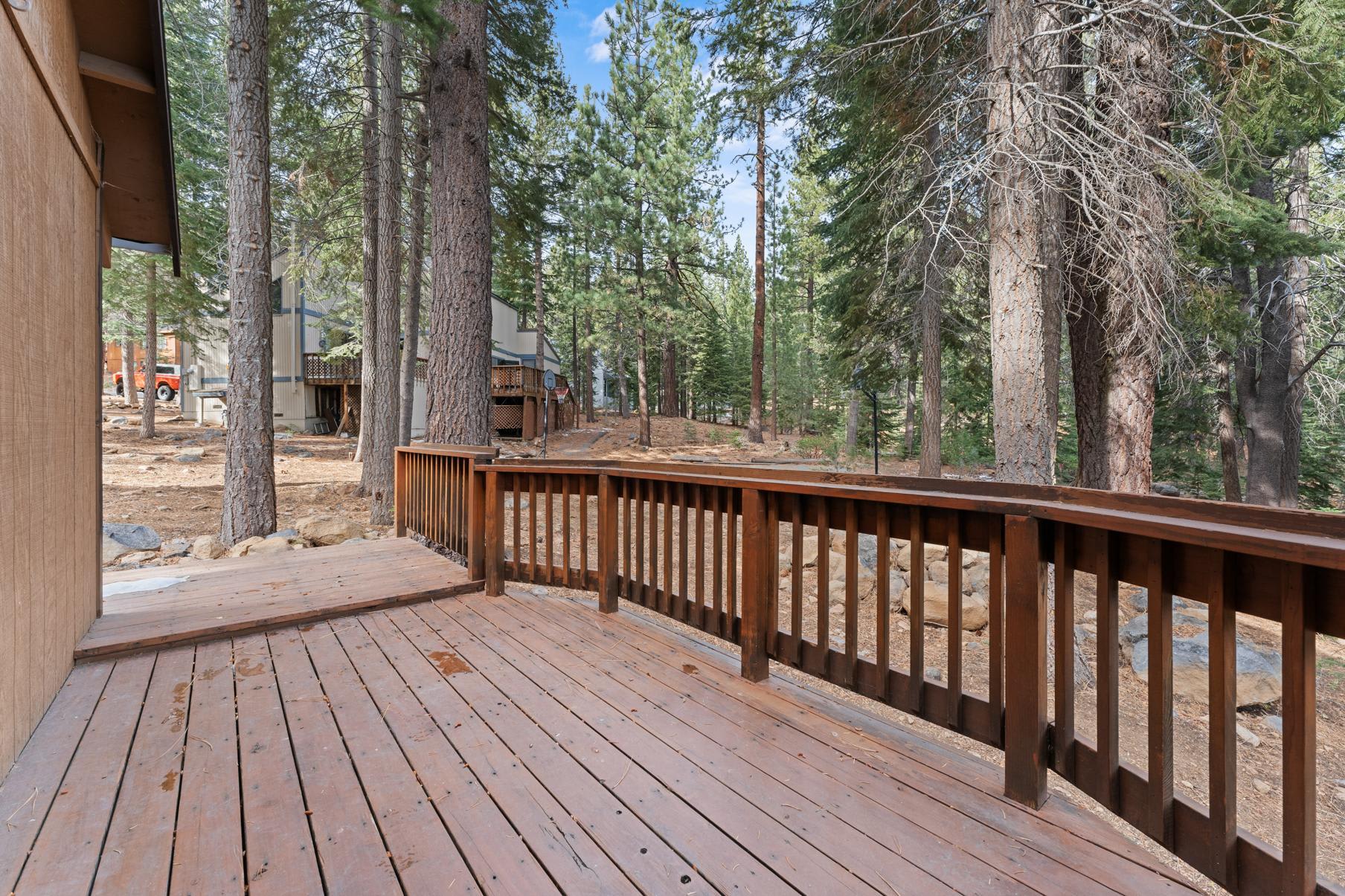 Wooden deck overlooking pine trees at a Truckee vacation rental, offering a serene forest view.