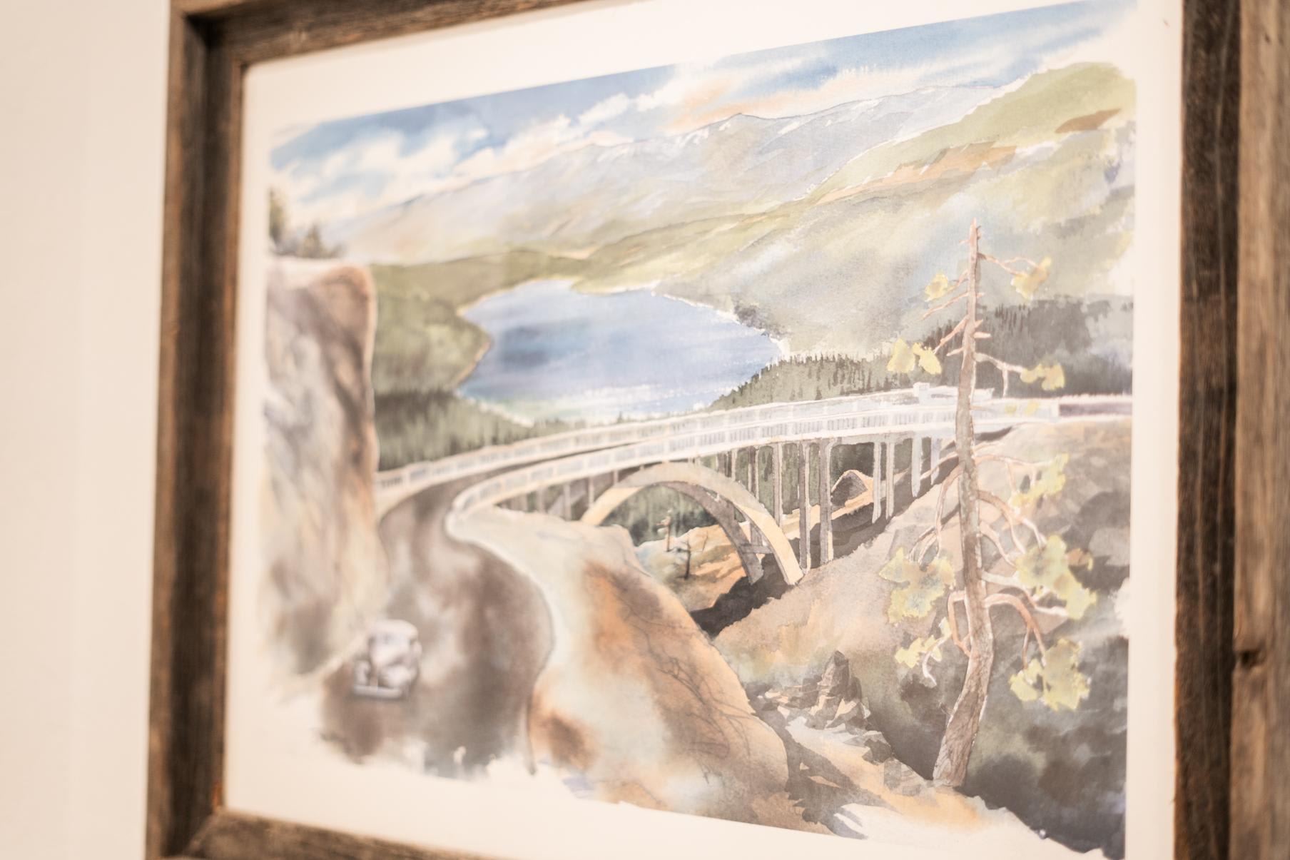 Watercolor painting on wall depicting Truckee's scenic bridge and lake, seen in a vacation rental.