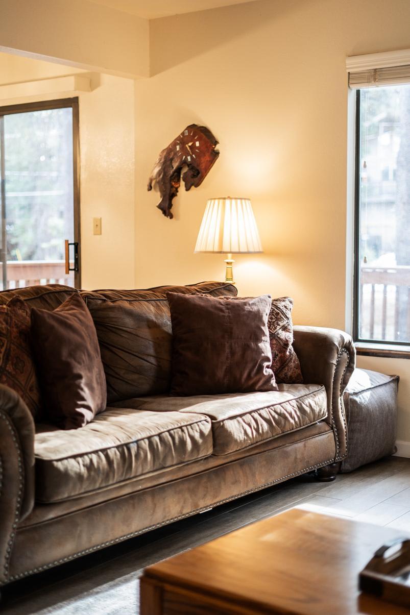 Cozy living room with plush sofa and warm lighting in a Truckee vacation rental, featuring rustic decor and large windows.