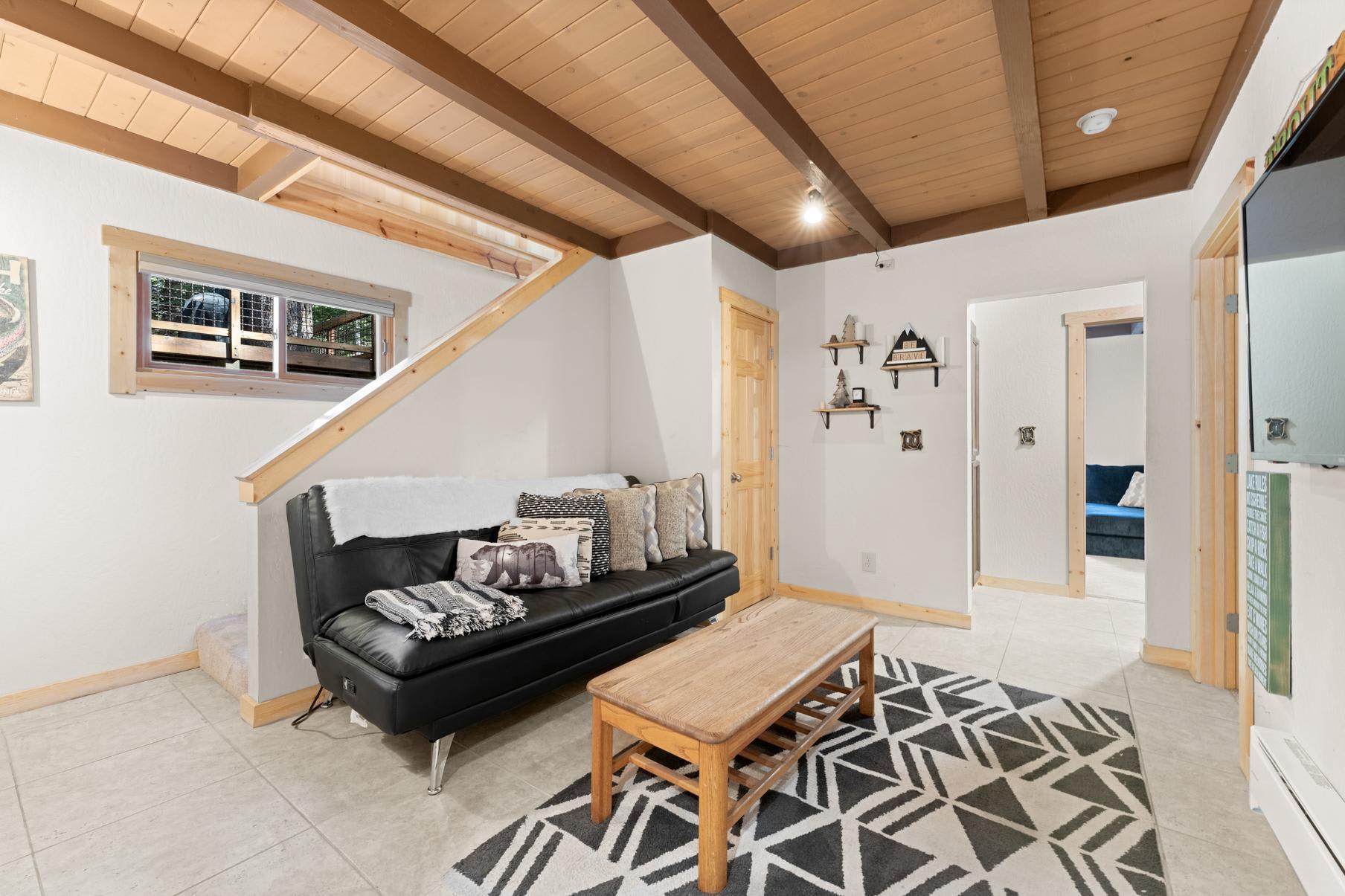 Cozy Truckee vacation rental with wood beam ceiling, modern decor, and a black sofa in the living area.