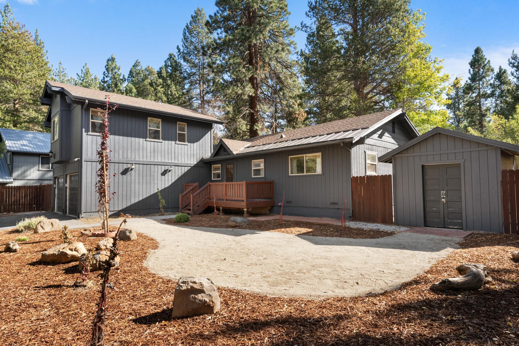 A cozy gray vacation rental in Truckee, featuring a two-story house with surrounding trees and a spacious yard.