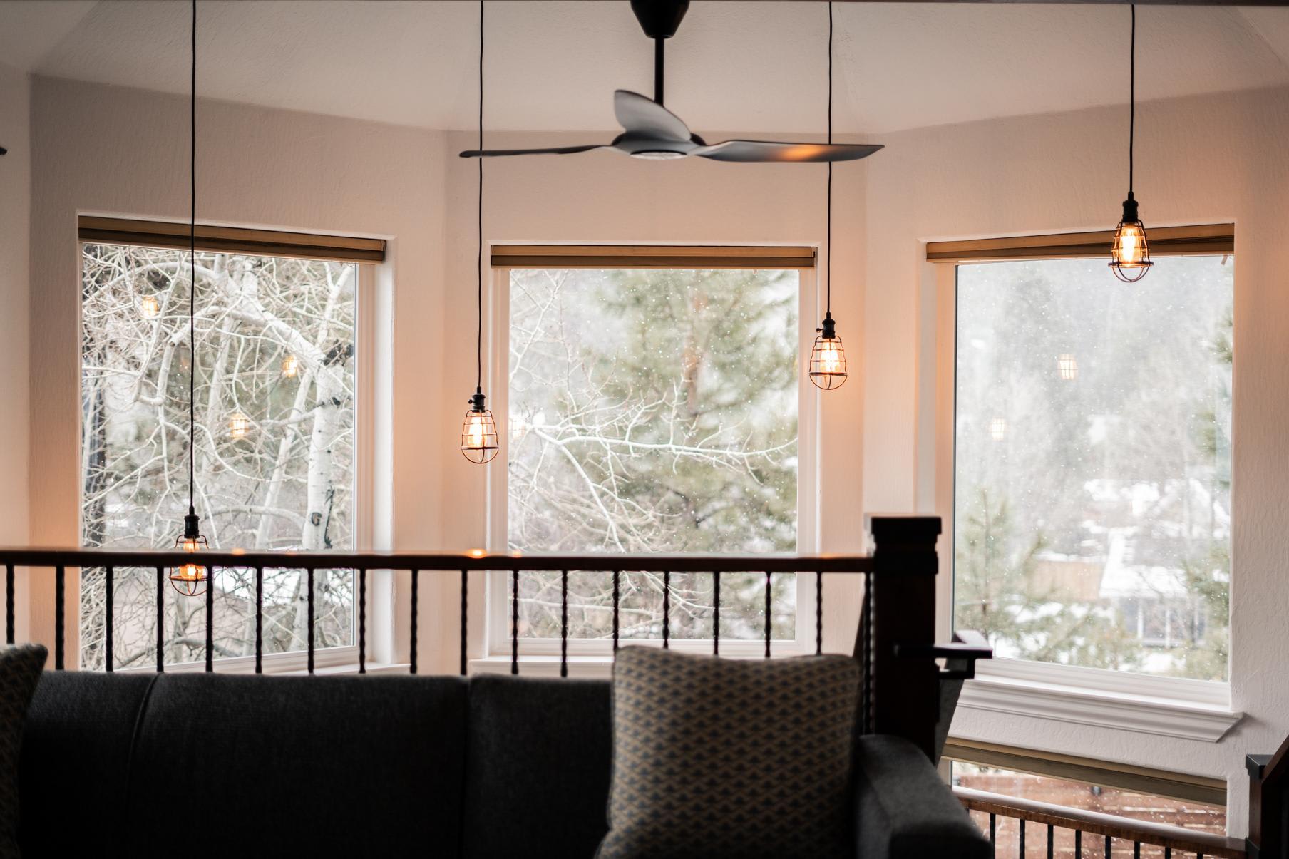 Cozy vacation rental in Truckee with large windows, forest views, and warm pendant lights over a comfortable seating area.