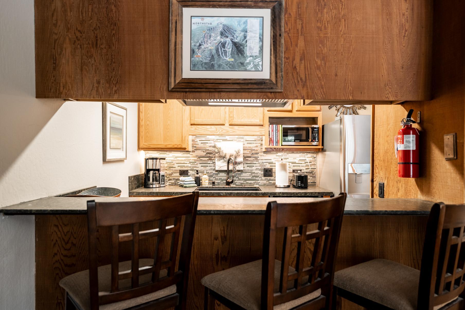 Truckee vacation rental kitchen with wooden cabinets, three barstools, and modern appliances.