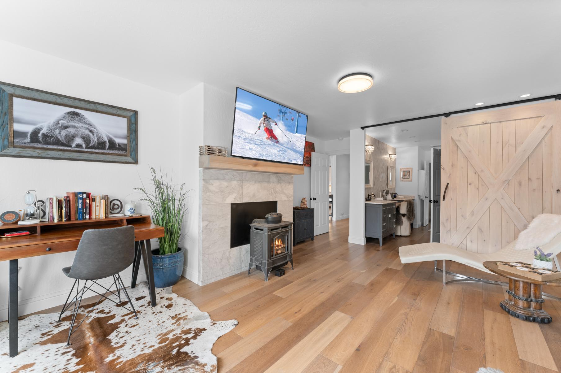 Modern Truckee vacation rental with cozy fireplace, stylish decor, desk area, and open bathroom view.