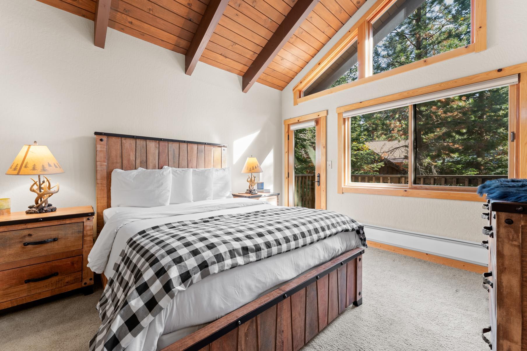 Cozy bedroom in a Truckee vacation rental with wood-paneled ceiling, large windows, and rustic furniture.