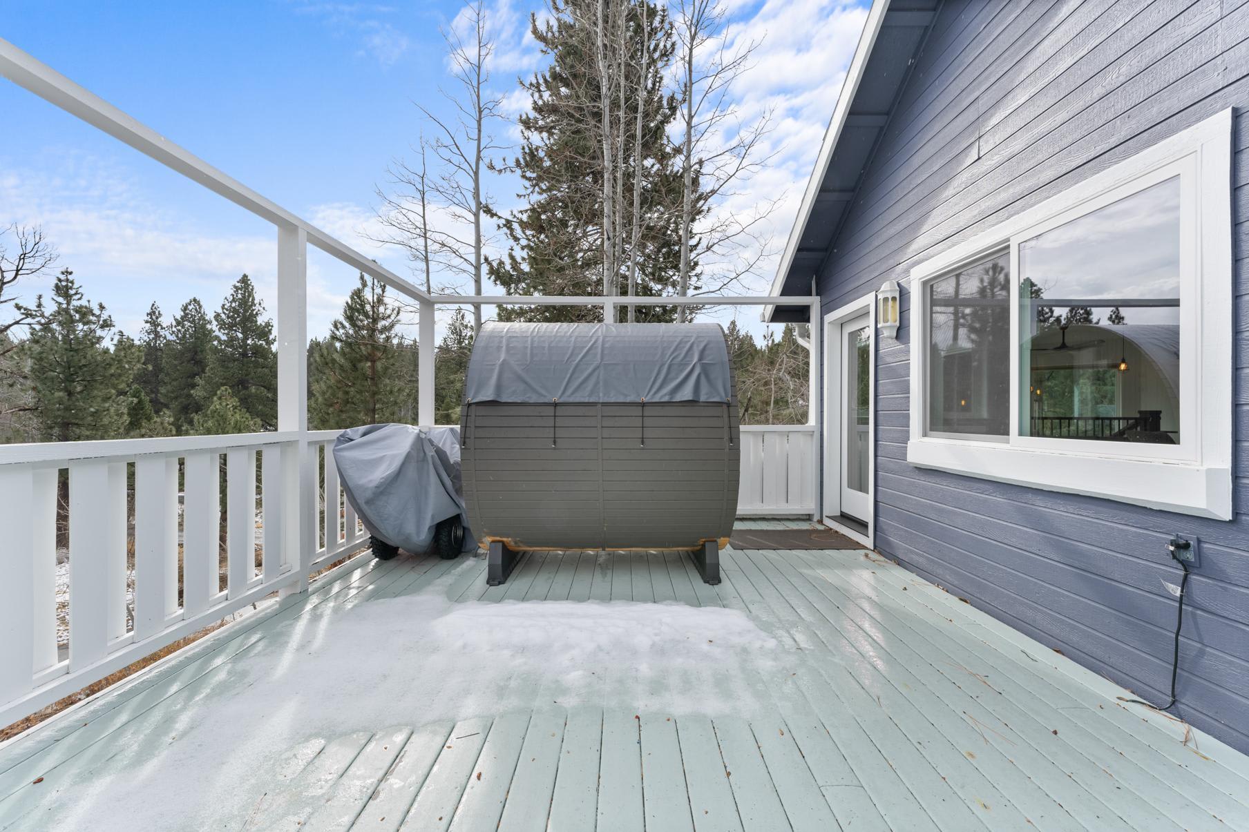 Deck view at a Truckee vacation rental with forest backdrop and covered hot tub.