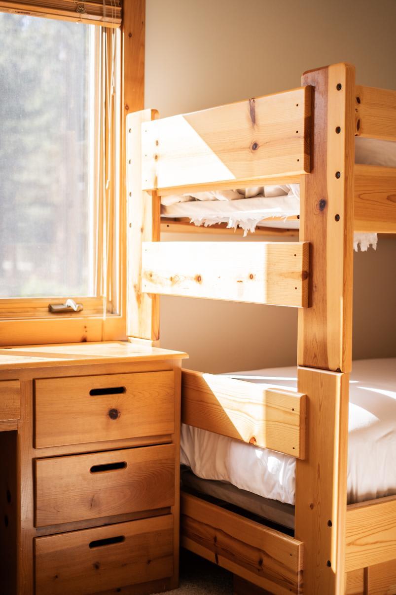 Cozy bunk beds and desk in a Truckee vacation rental, with sunlight streaming through a nearby window.