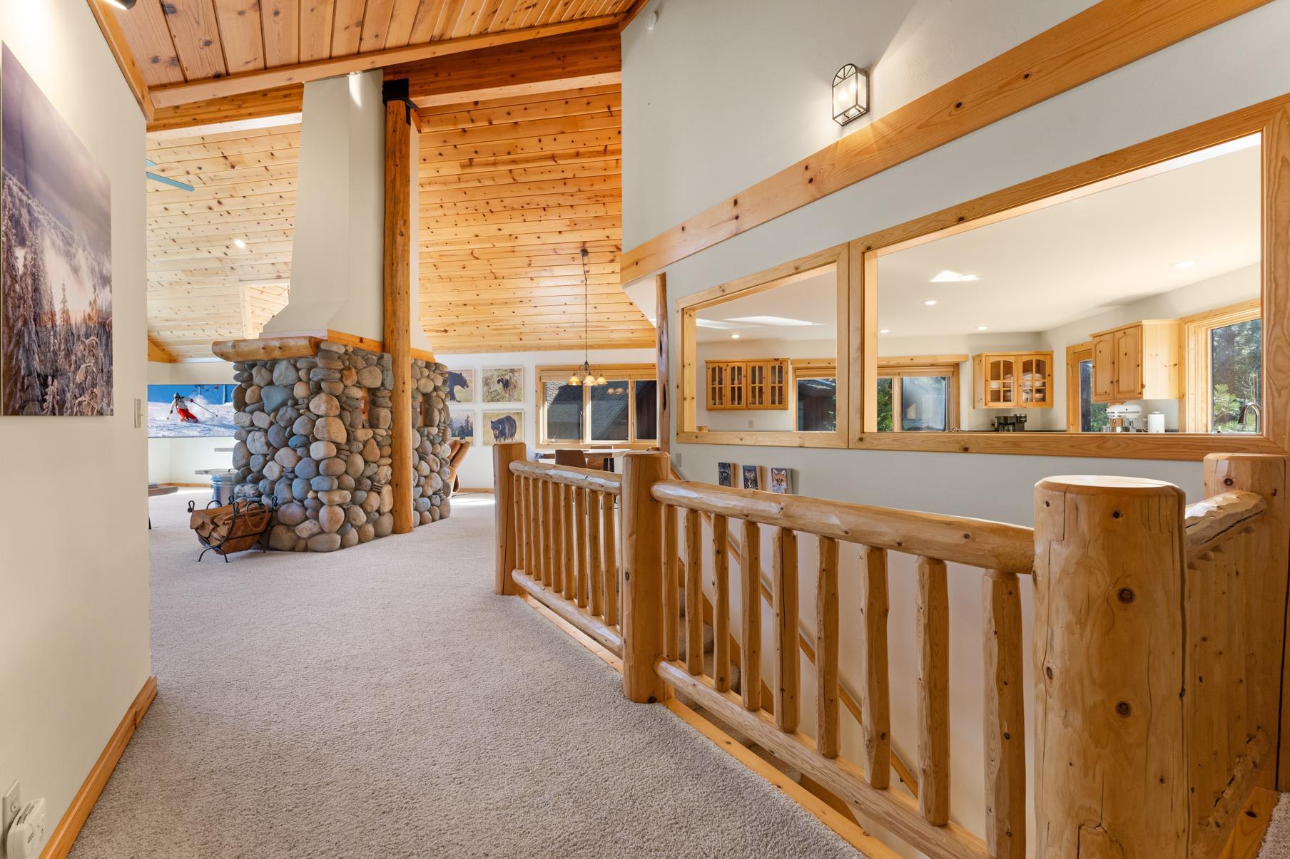 Rustic interior of a Truckee vacation rental featuring a large stone fireplace and wooden details throughout.