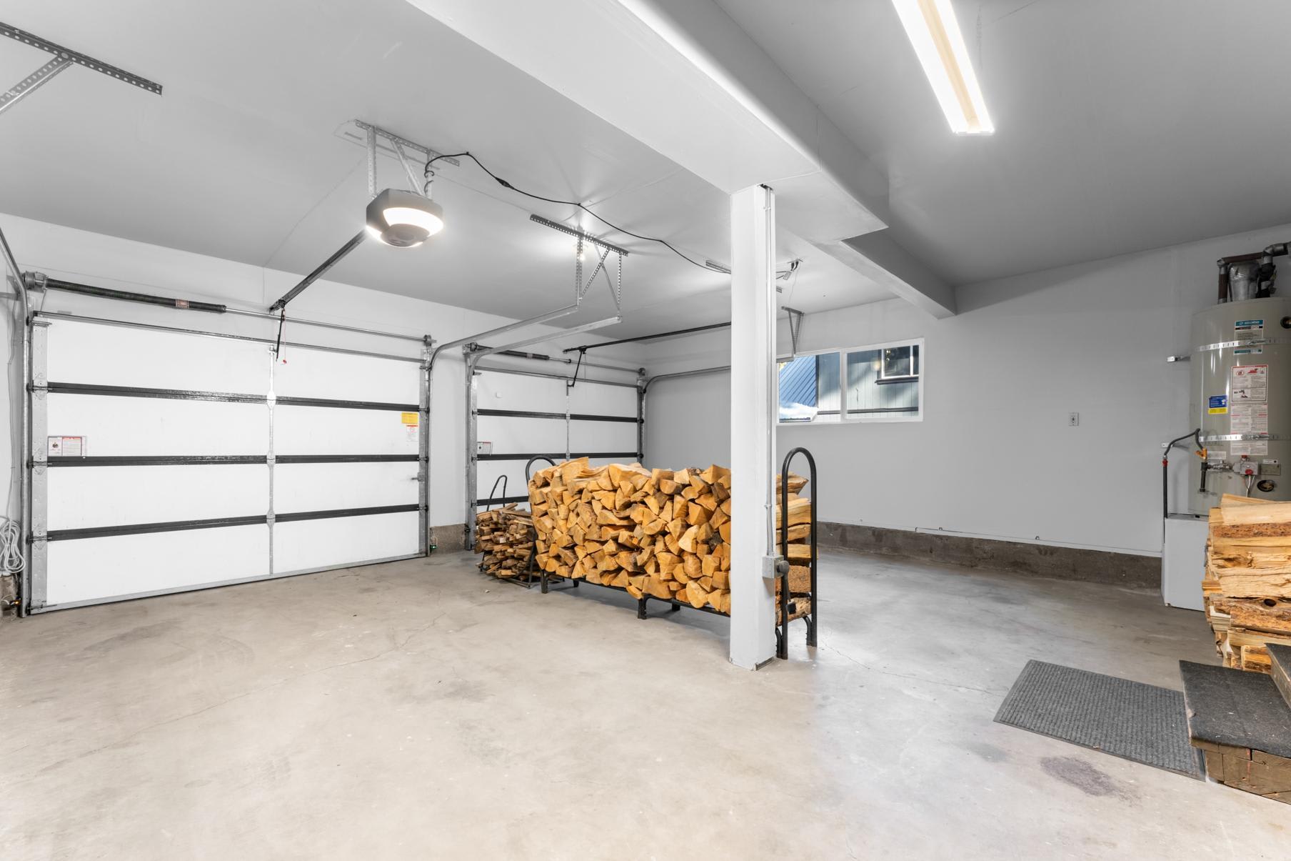 Spacious garage in a Truckee vacation rental with wood storage, concrete floor, and white walls.