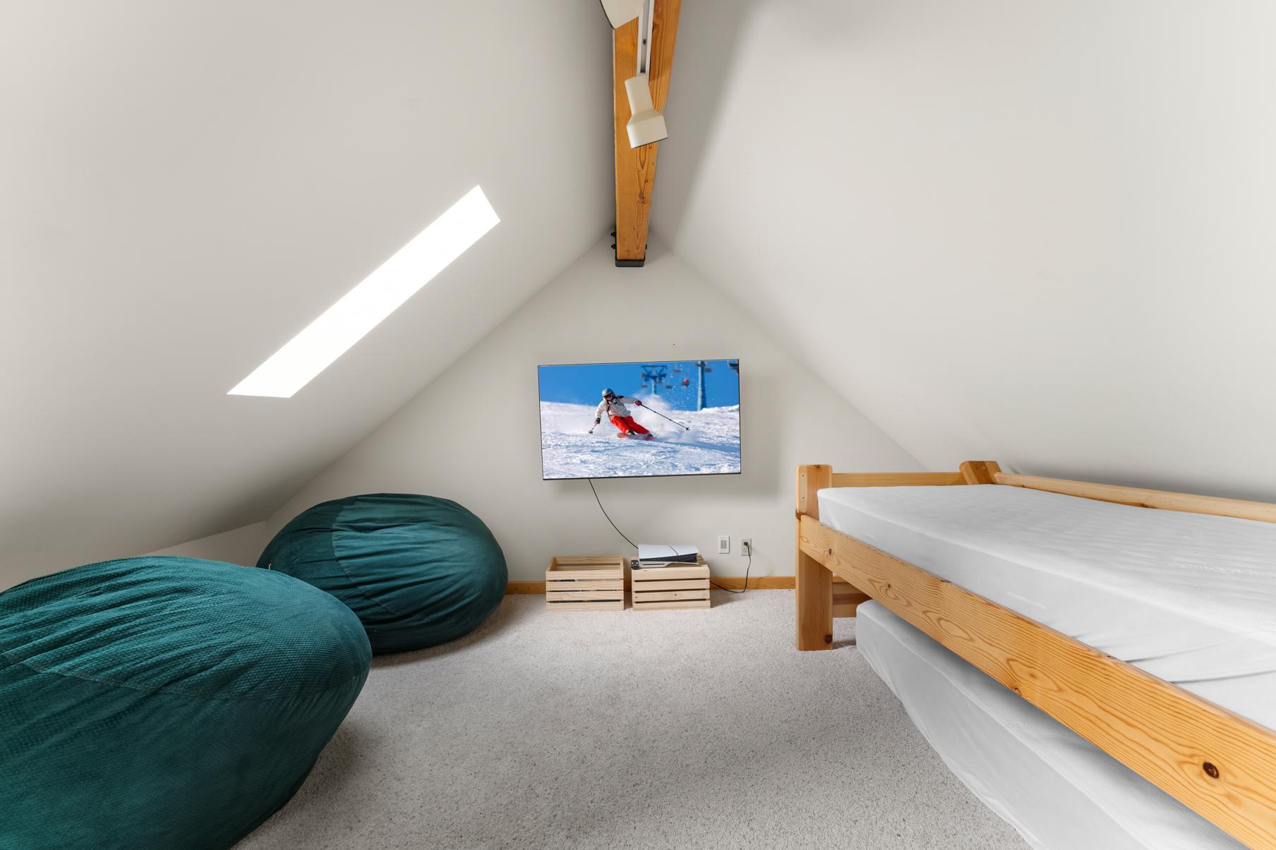 Loft space in Truckee vacation rental with bean bags, a bunk bed, and a TV displaying a skiing scene.