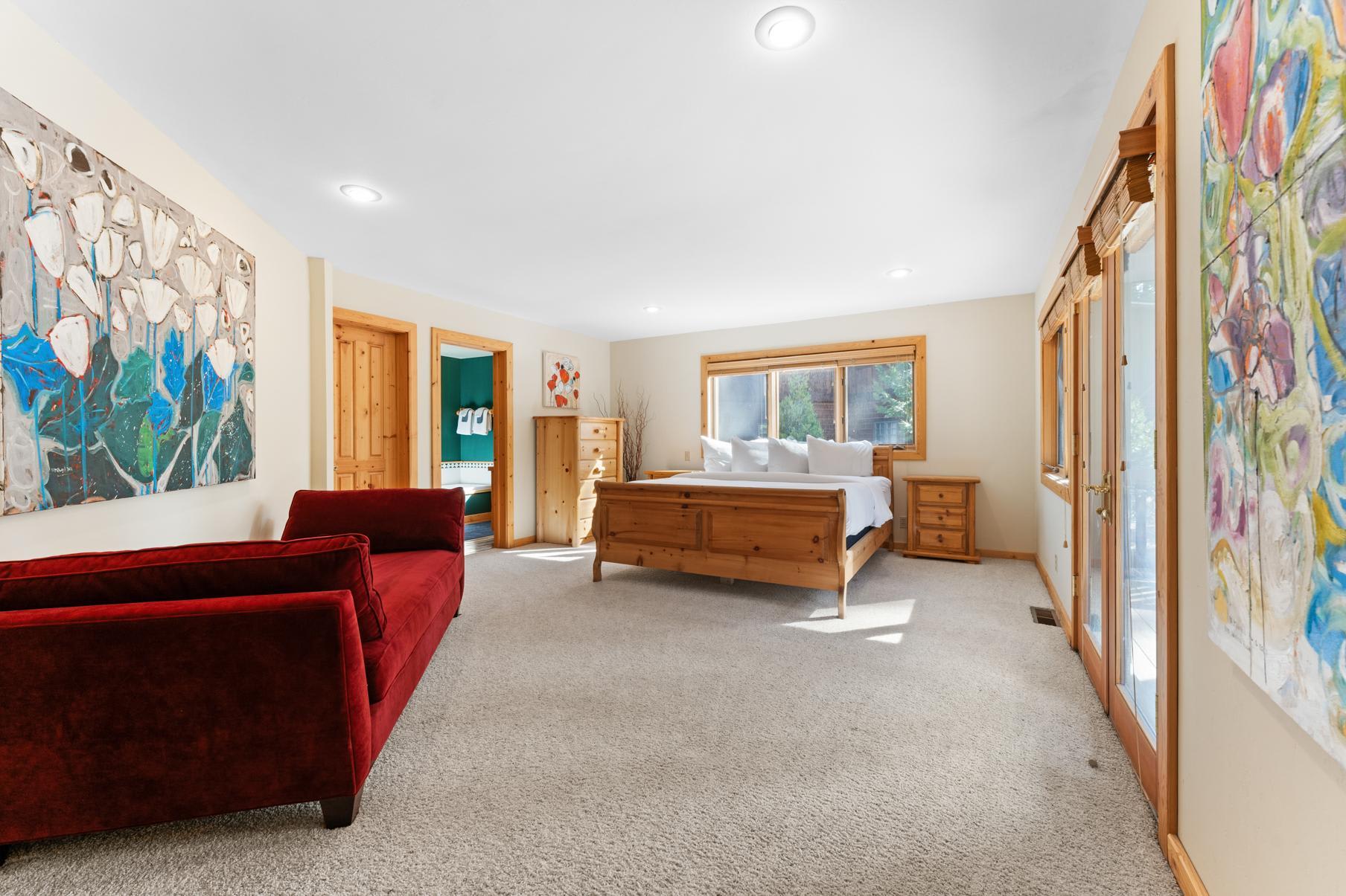 Bedroom with artwork, red sofa, and wooden furniture in a Truckee vacation rental. Bright and spacious interior.