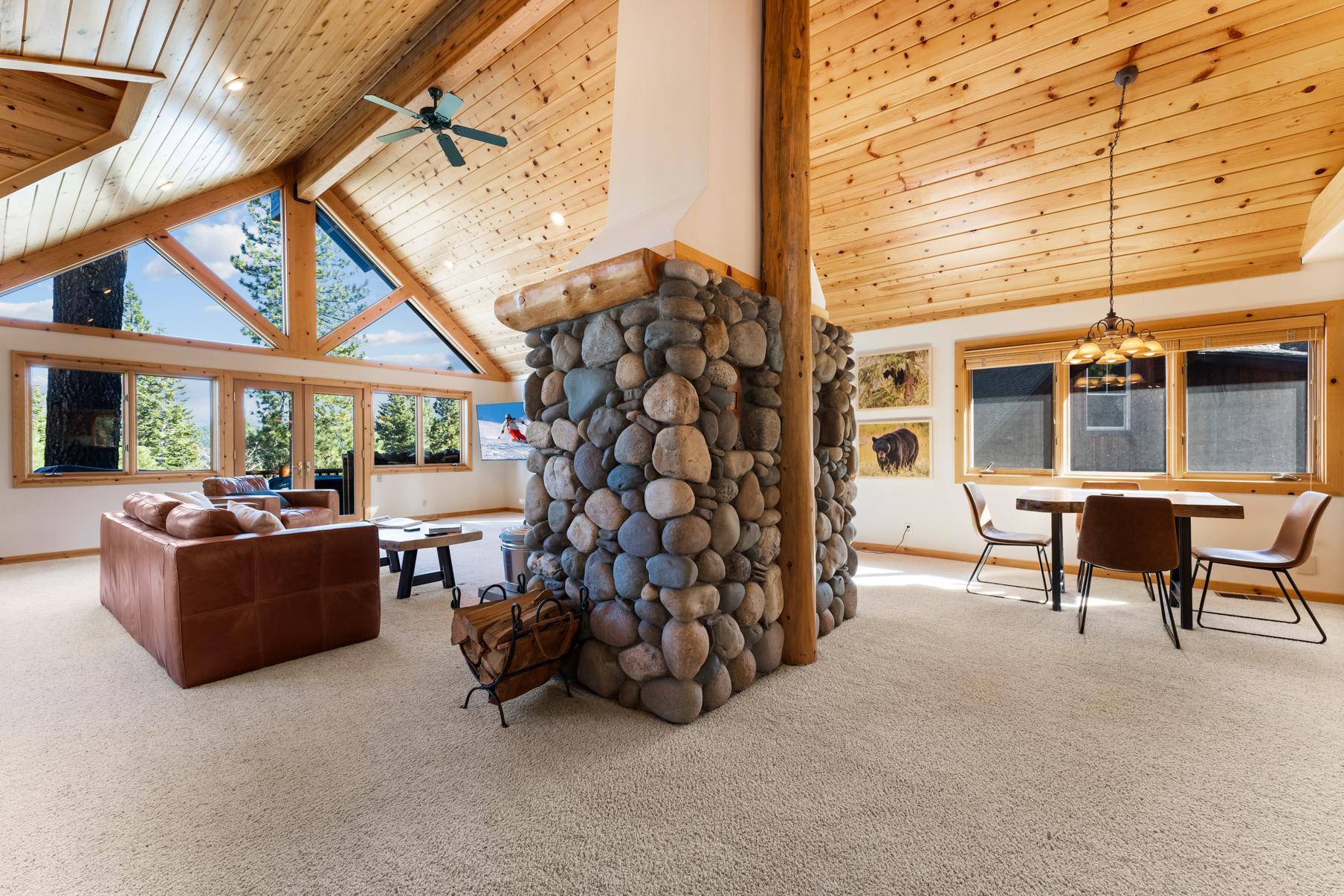 Spacious Truckee vacation rental with wood interior, stone fireplace, and large windows showcasing scenic forest views.