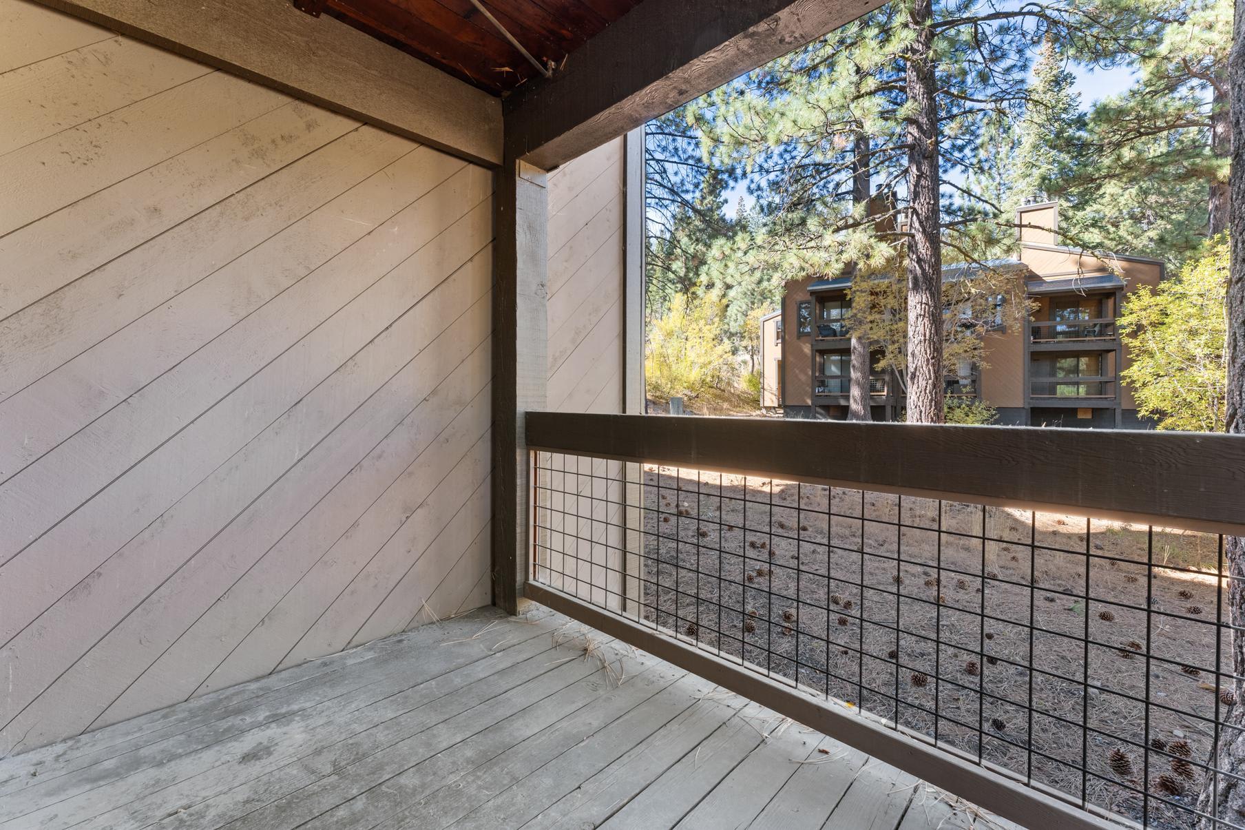 Balcony view from a Truckee vacation rental, overlooking pine trees and a neighboring building.