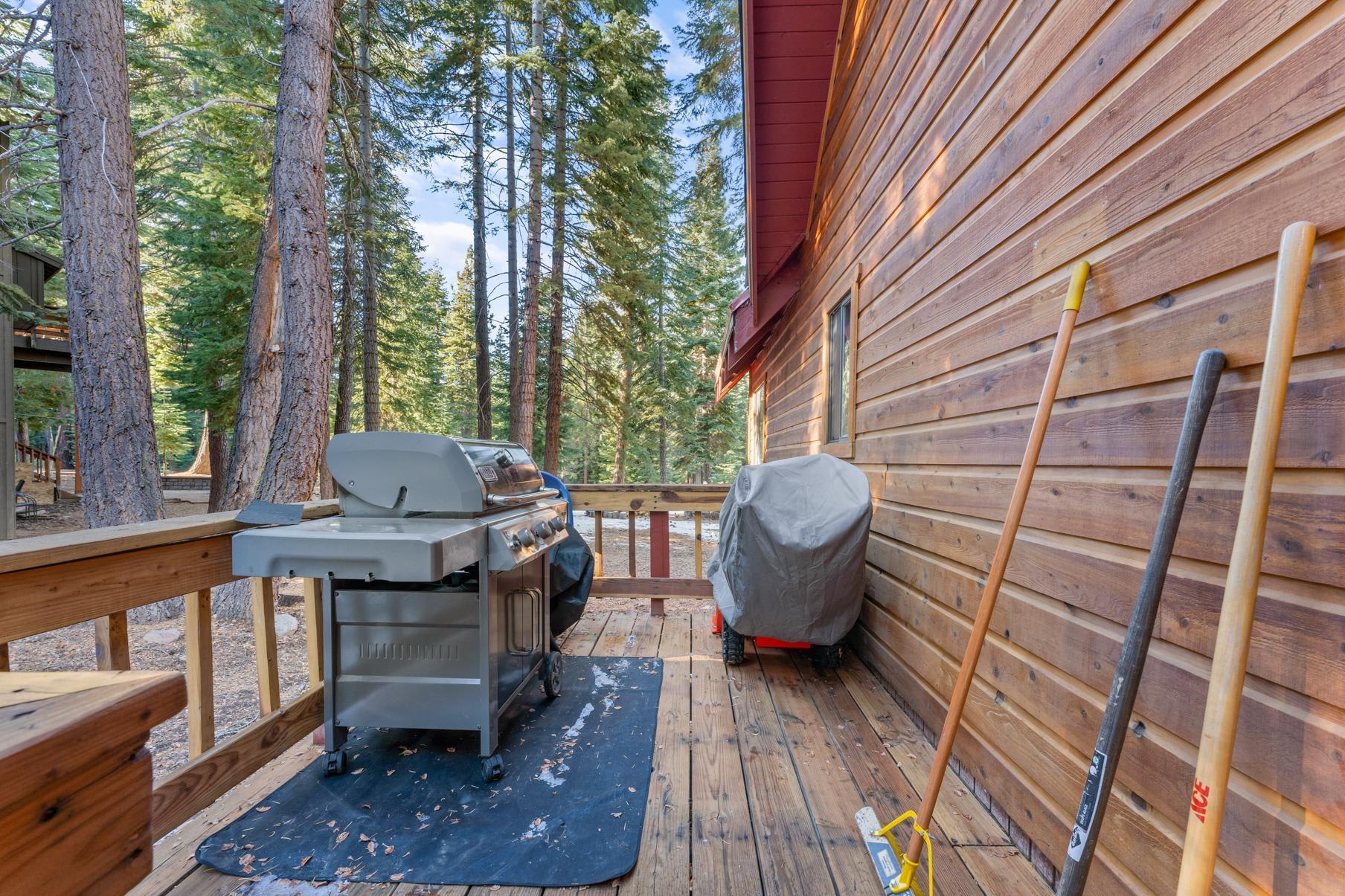 Wooden deck at a Tahoe Vista vacation rental, featuring a barbecue grill and surrounded by tall trees.