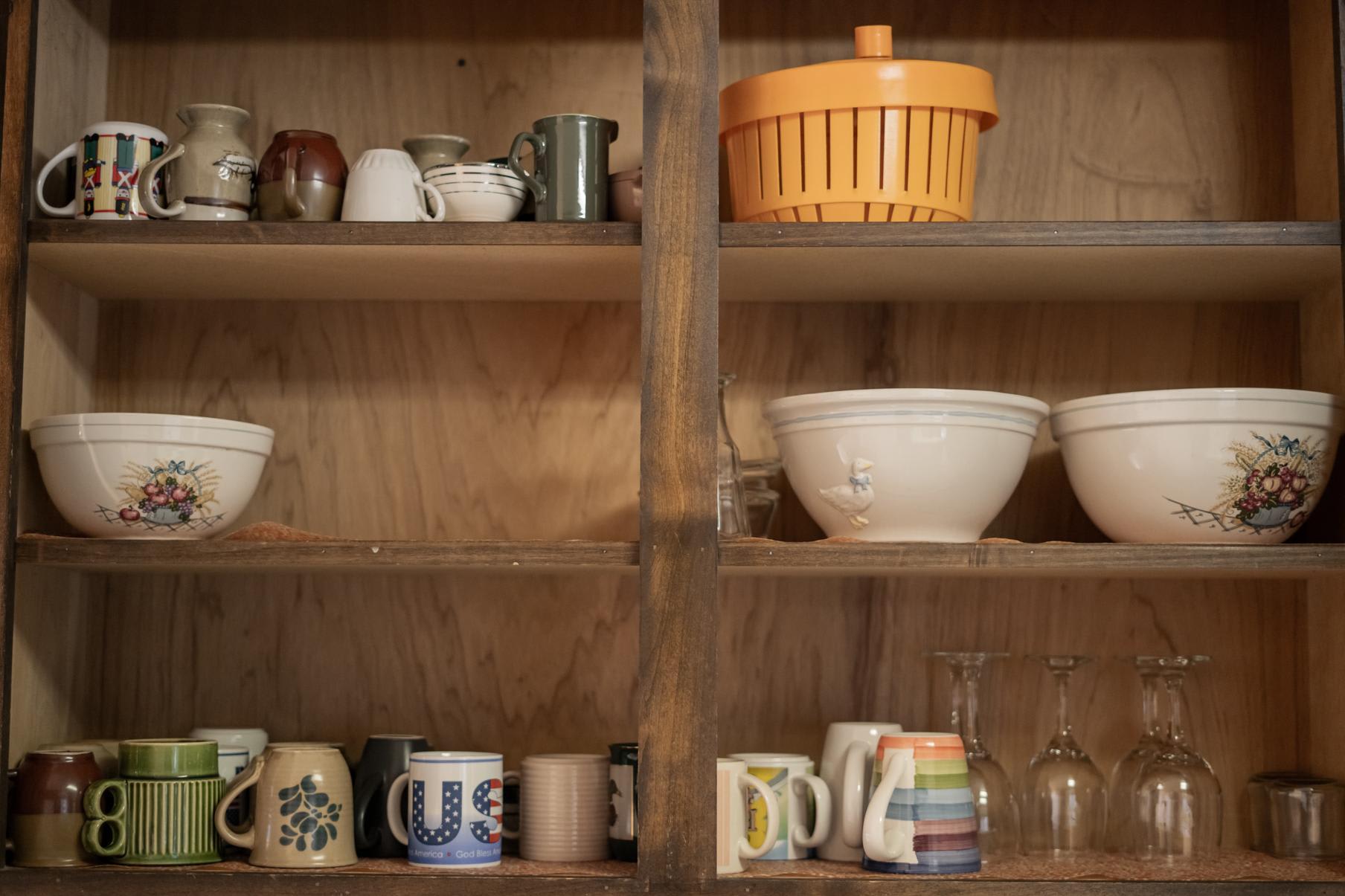 Cabinet in Truckee vacation rental with eclectic mugs and bowls on wooden shelves.