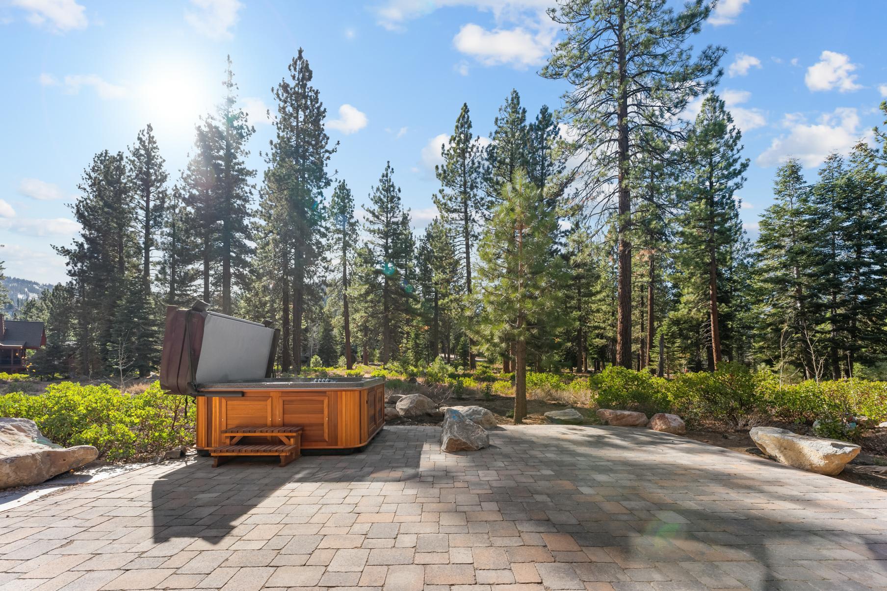 Vacation rental in Truckee with a patio and hot tub surrounded by pine trees under a clear blue sky.