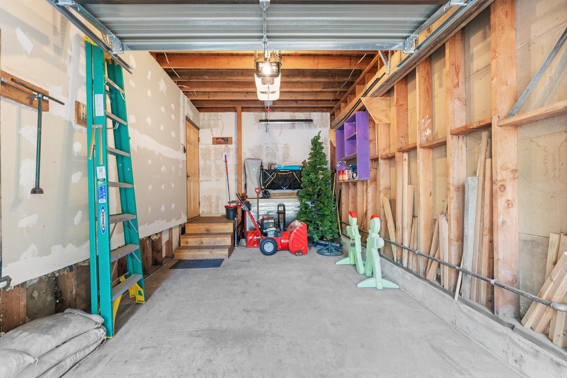 Garage in Truckee vacation rental with tools, a ladder, and seasonal decor neatly organized against unfinished walls.