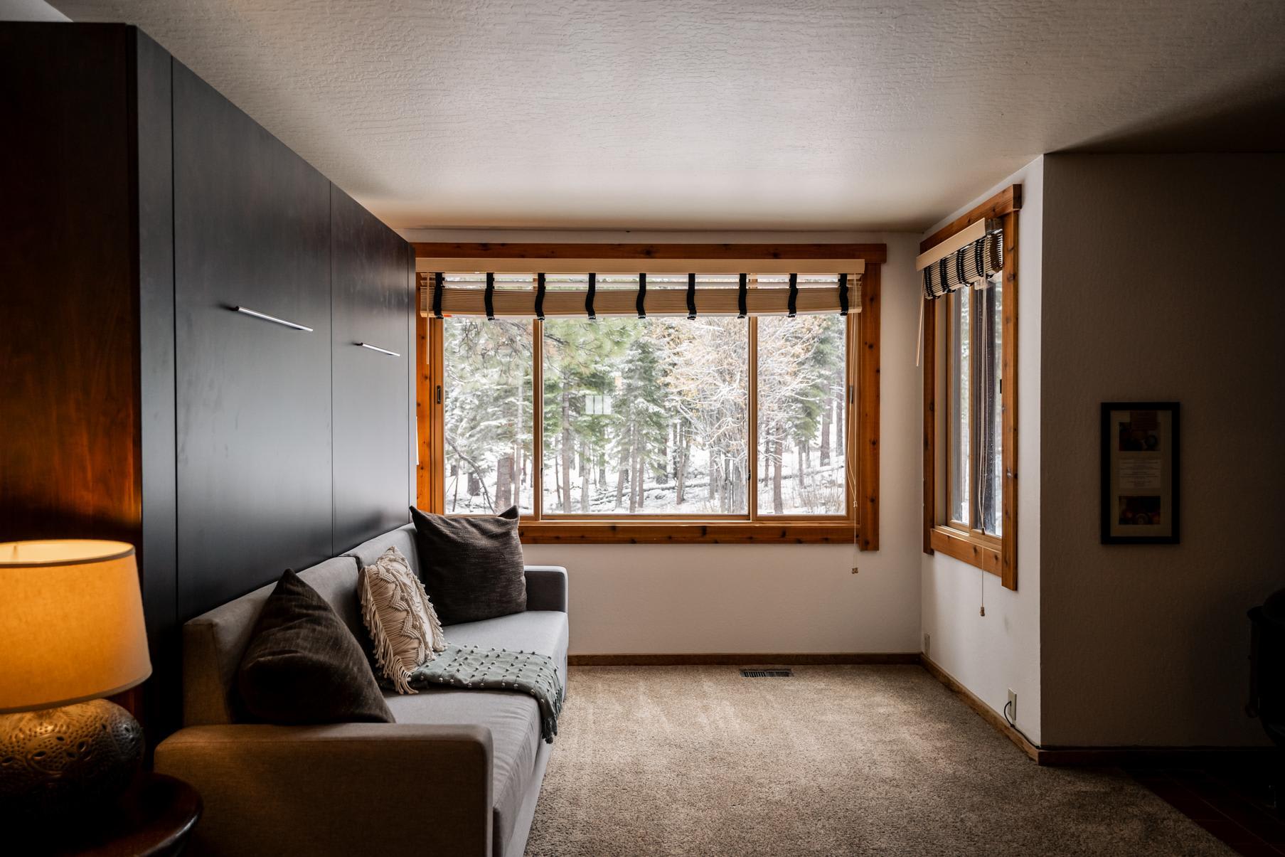 Cozy Truckee vacation rental with a sofa and large windows offering a snowy forest view.