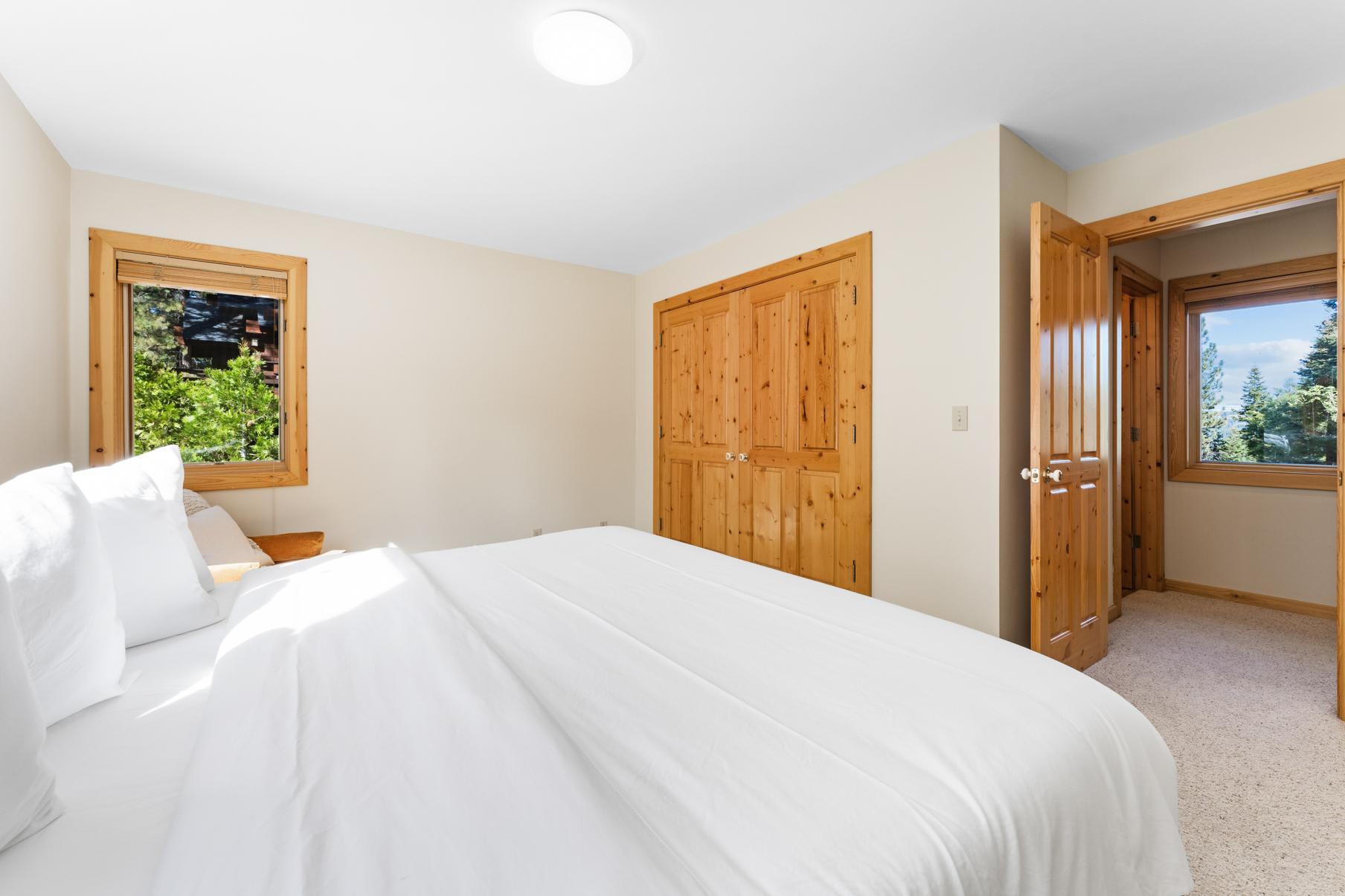 Bedroom with a large bed, wooden doors, and window view in a Truckee vacation rental.