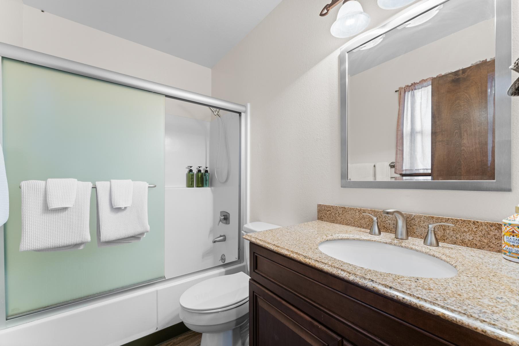 Bathroom in a Truckee vacation rental with a shower, granite countertop, and large mirror.