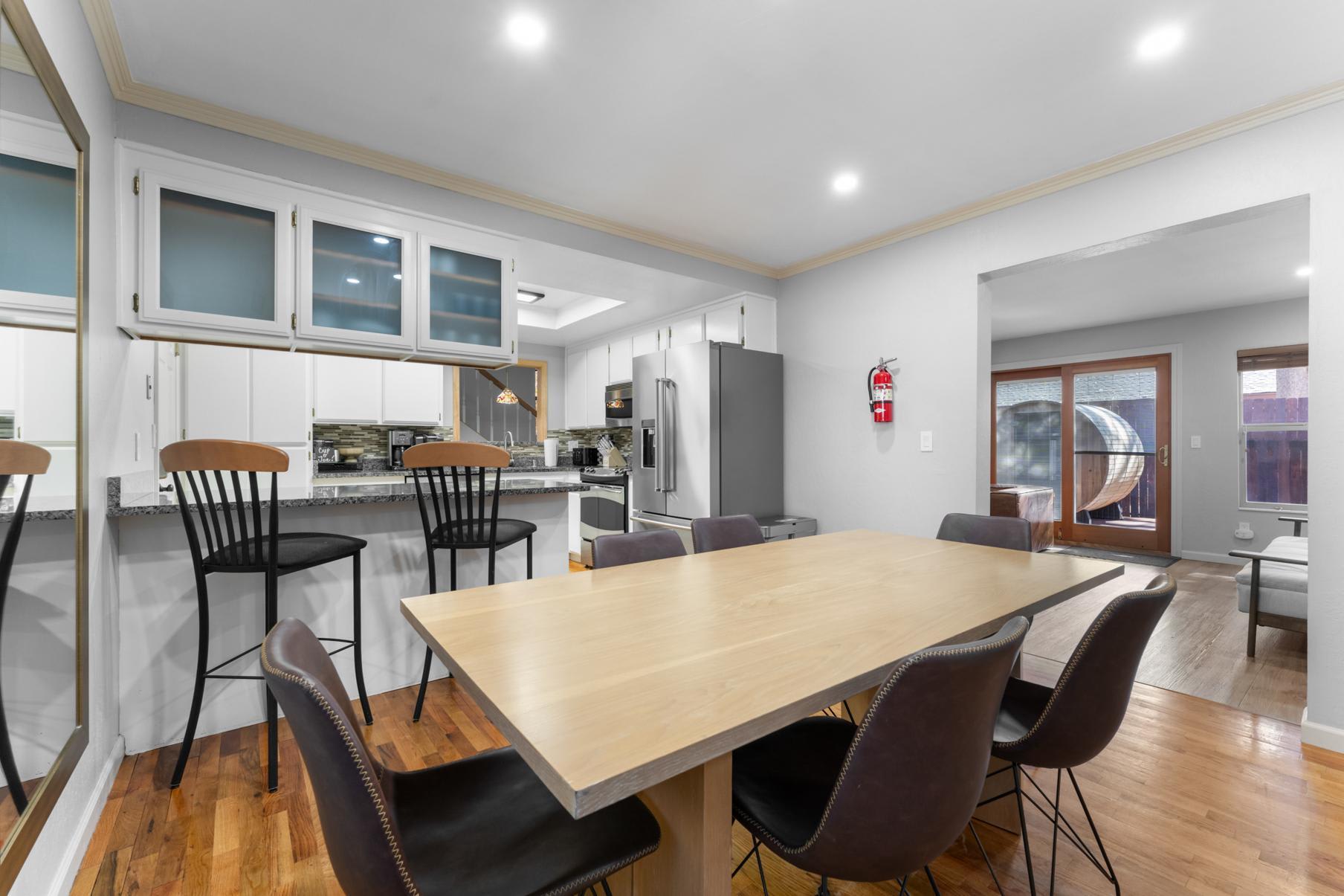 Modern kitchen and dining area in a Truckee vacation rental, featuring a wooden table, chairs, and a view of the patio.