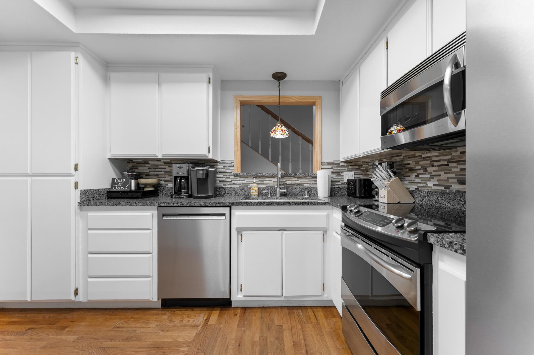 Modern kitchen in a Truckee vacation rental with white cabinets, stainless appliances, and wooden floor.