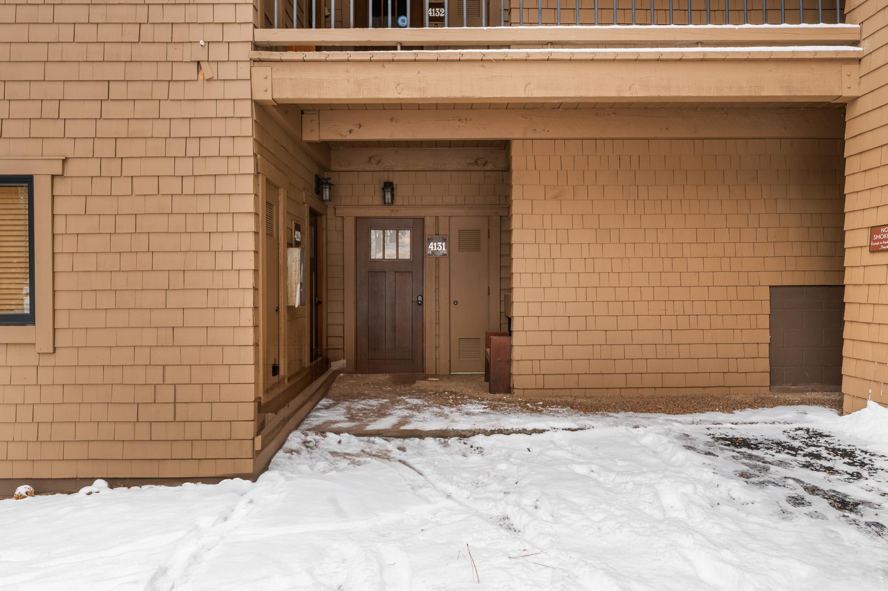 Entrance to a vacation rental in Truckee, with brown wooden siding and snow on the ground.