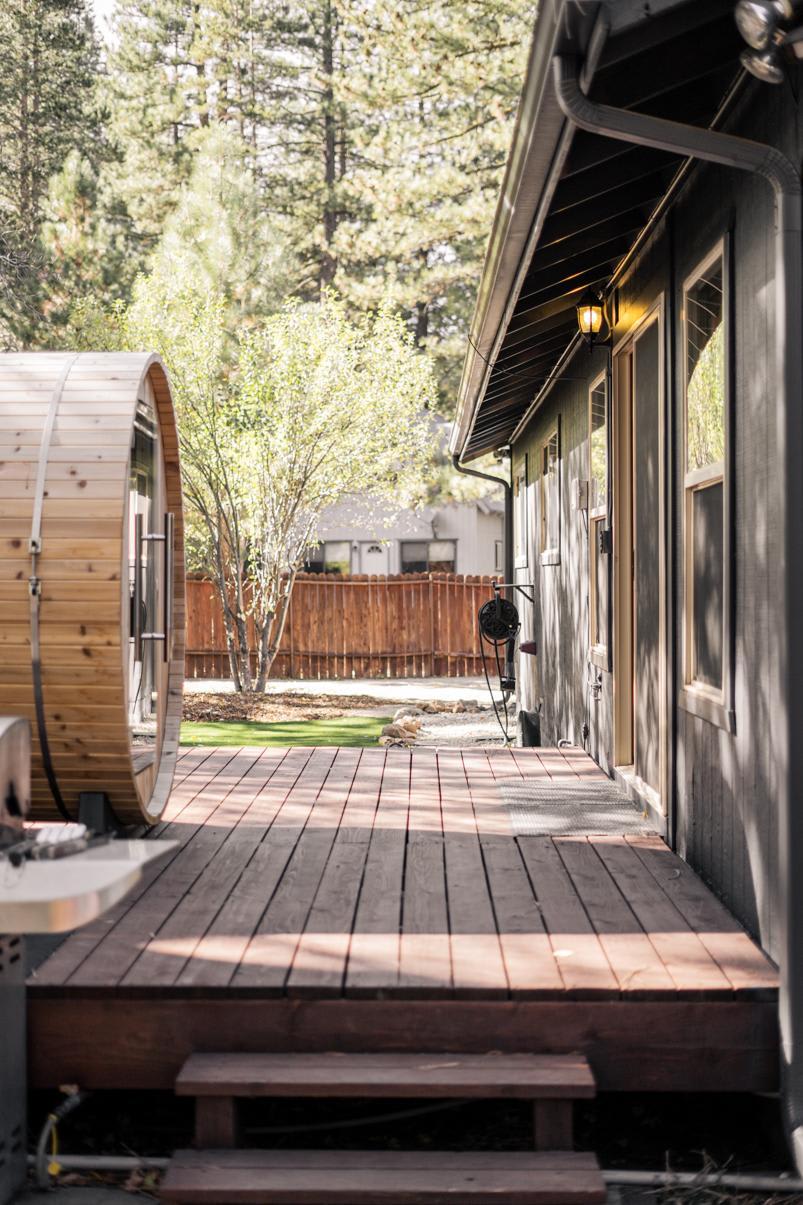 Wooden deck and sauna at a Truckee vacation rental, surrounded by trees and fenced yard.