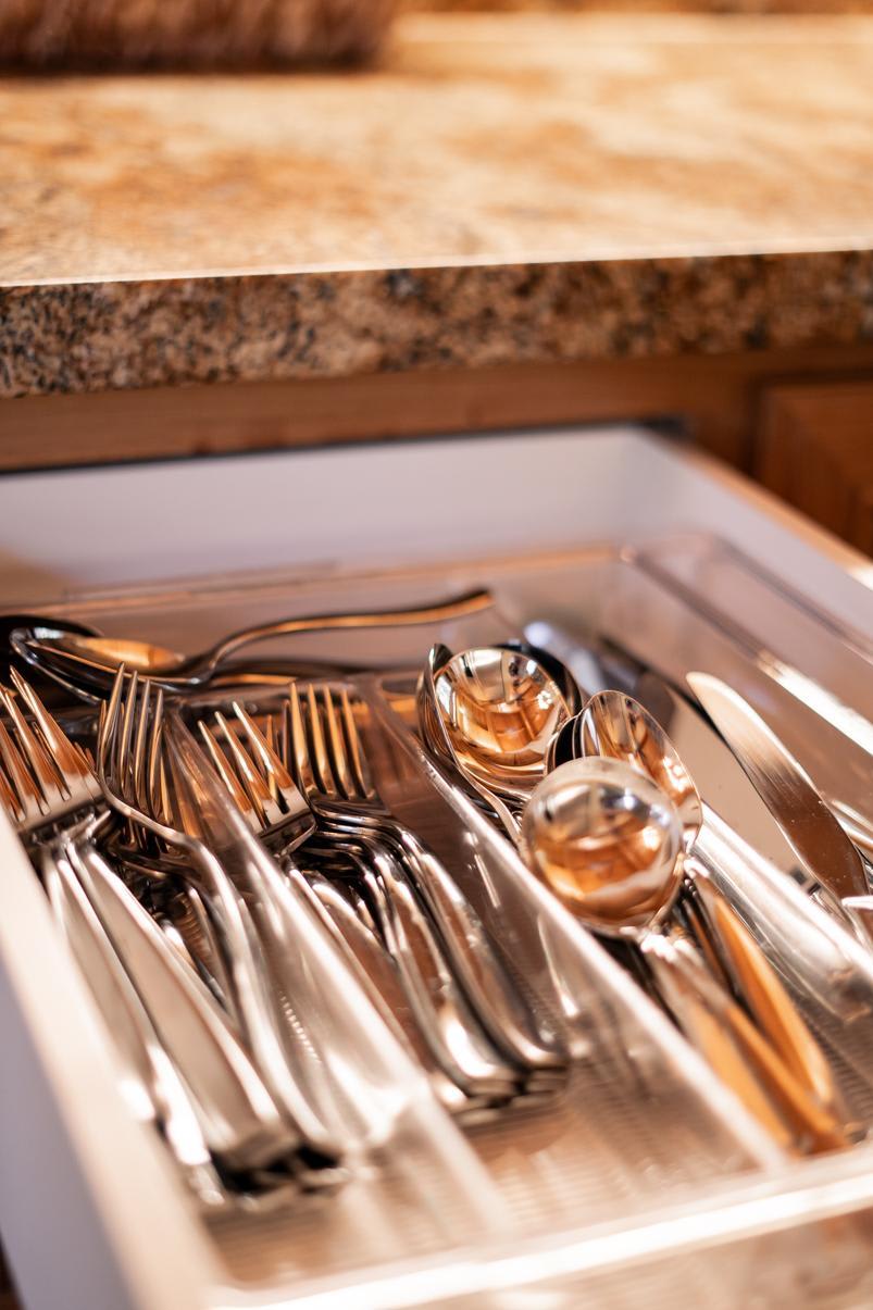 Open kitchen drawer with silverware in a Truckee vacation rental, granite countertop above.