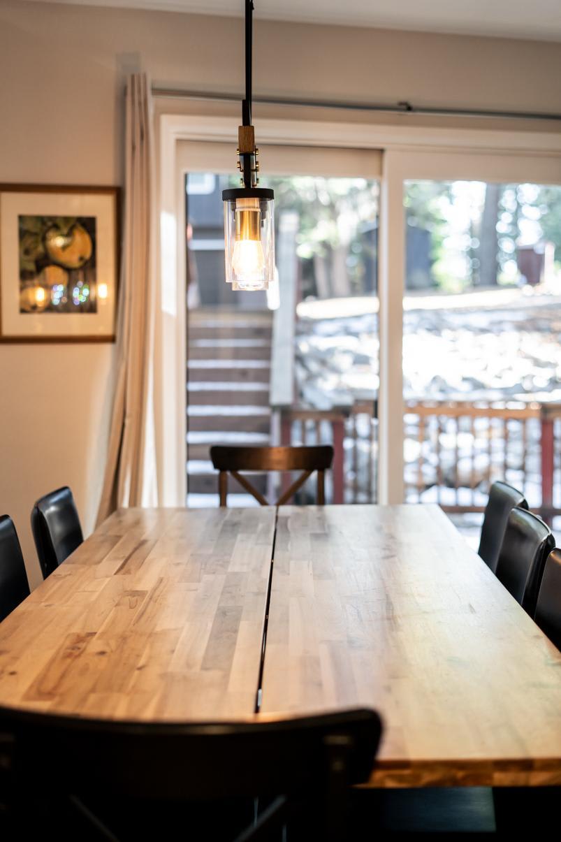 Dining area in Tahoe Vista vacation rental, featuring a wooden table, chairs, and a pendant light by large sliding doors.