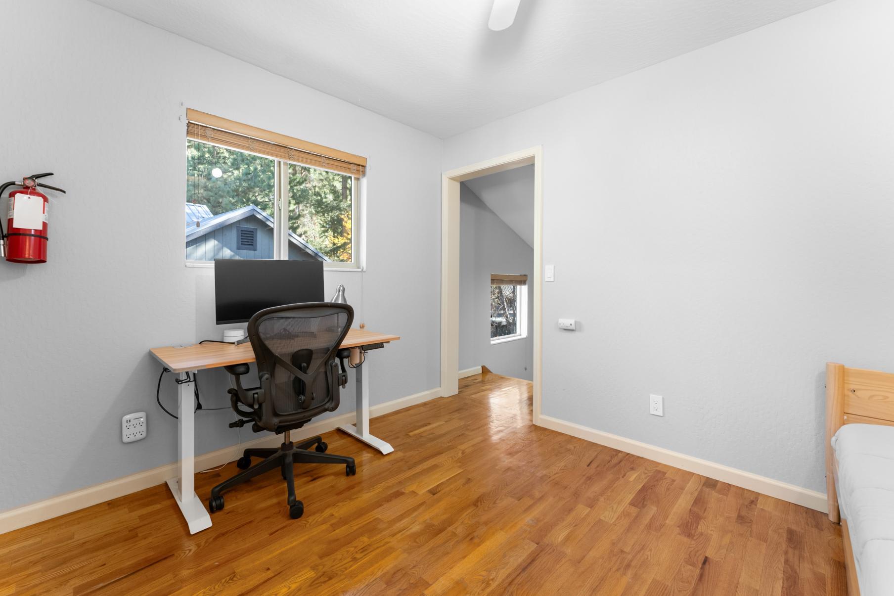 Modern office space in a Truckee vacation rental with a desk, chair, and window view of trees.