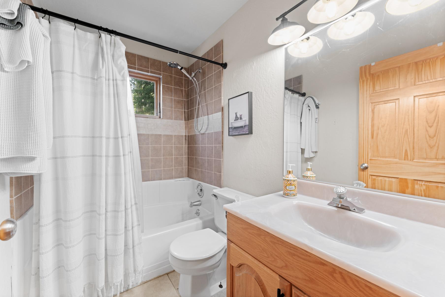 Bathroom in a Truckee vacation rental with a tiled bathtub, shower, and vanity with a mirrored light fixture.