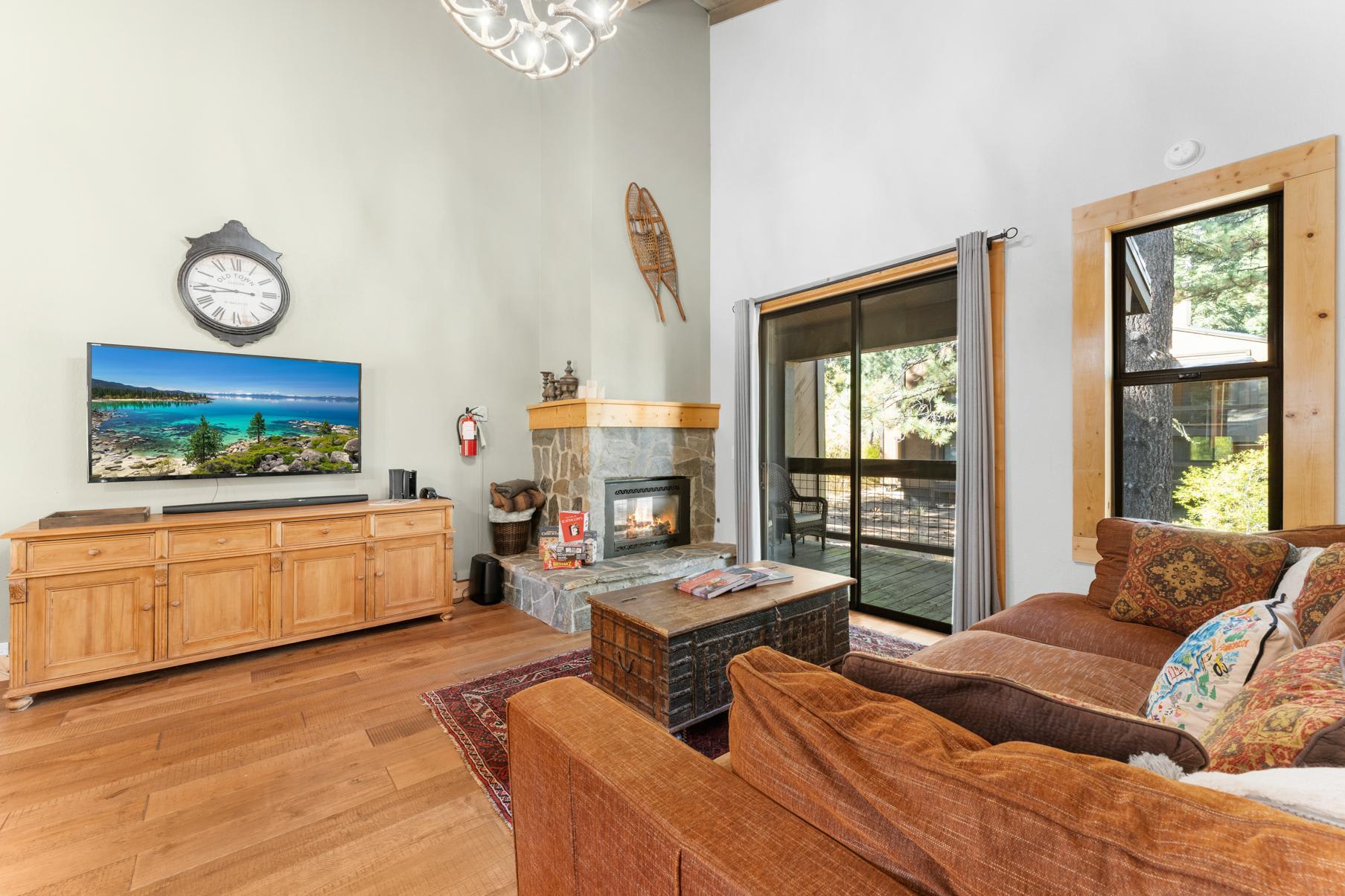 Cozy Truckee vacation rental living room with a fireplace, TV, rustic decor, and patio view.