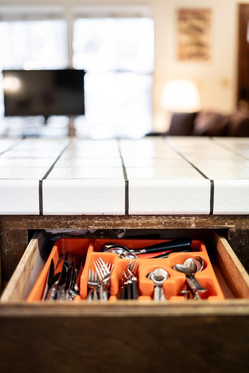 Kitchen drawer with cutlery in a Truckee vacation rental, tiled counter and blurred background.