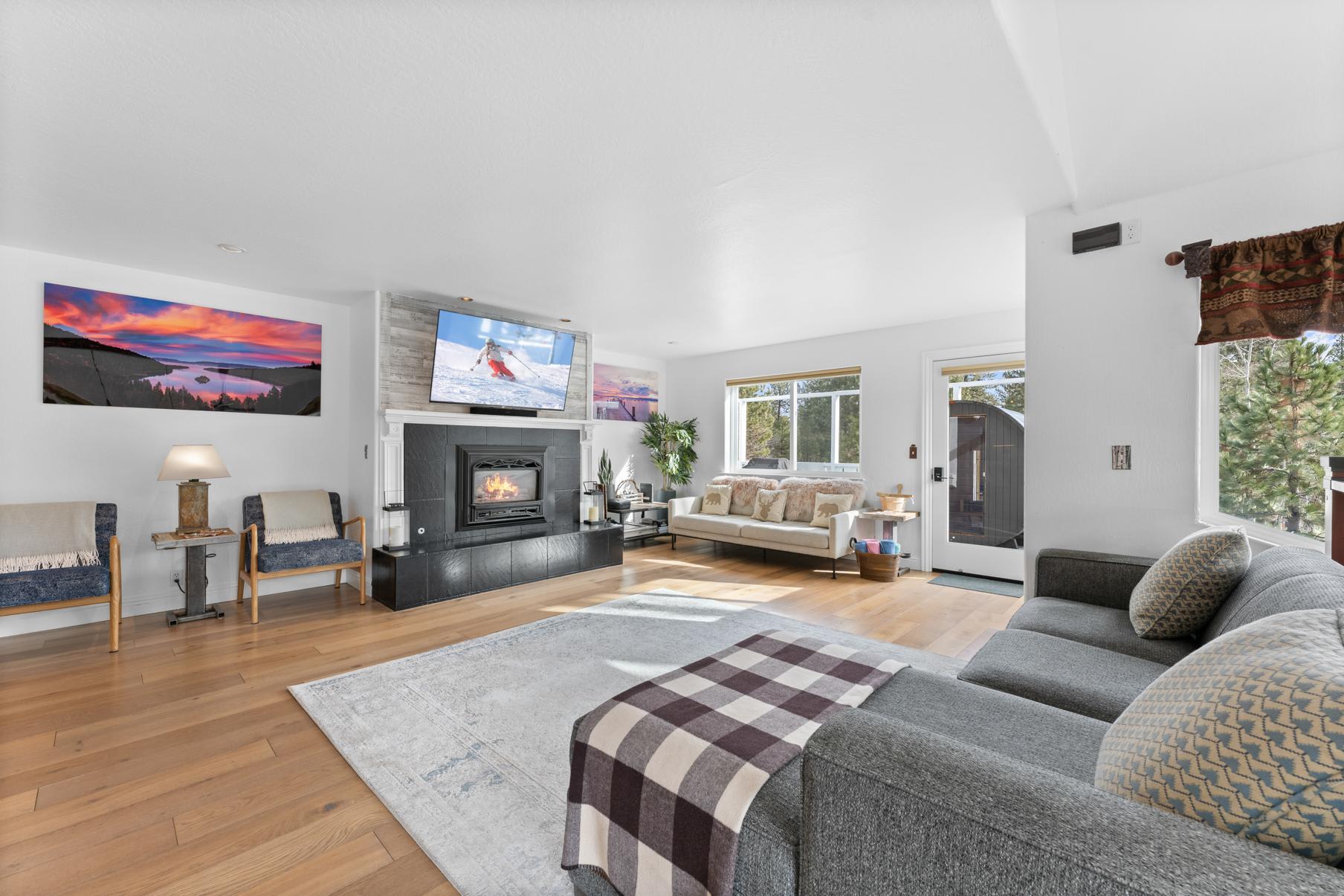 Cozy living room in a Truckee vacation rental with a fireplace, modern decor, and large windows overlooking the outdoors.