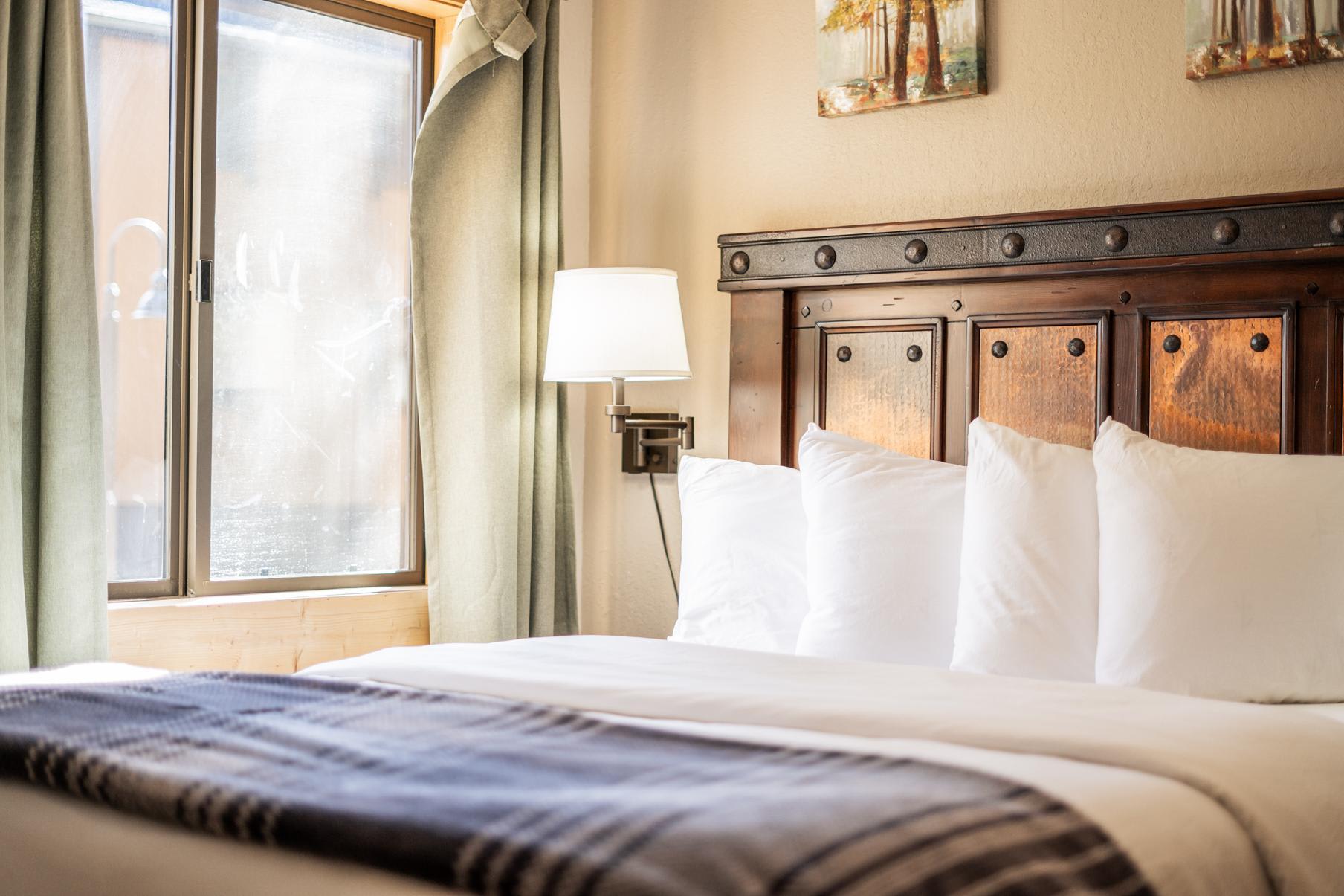 Cozy bedroom in a Truckee vacation rental with a wooden headboard, soft pillows, and natural light from a window.