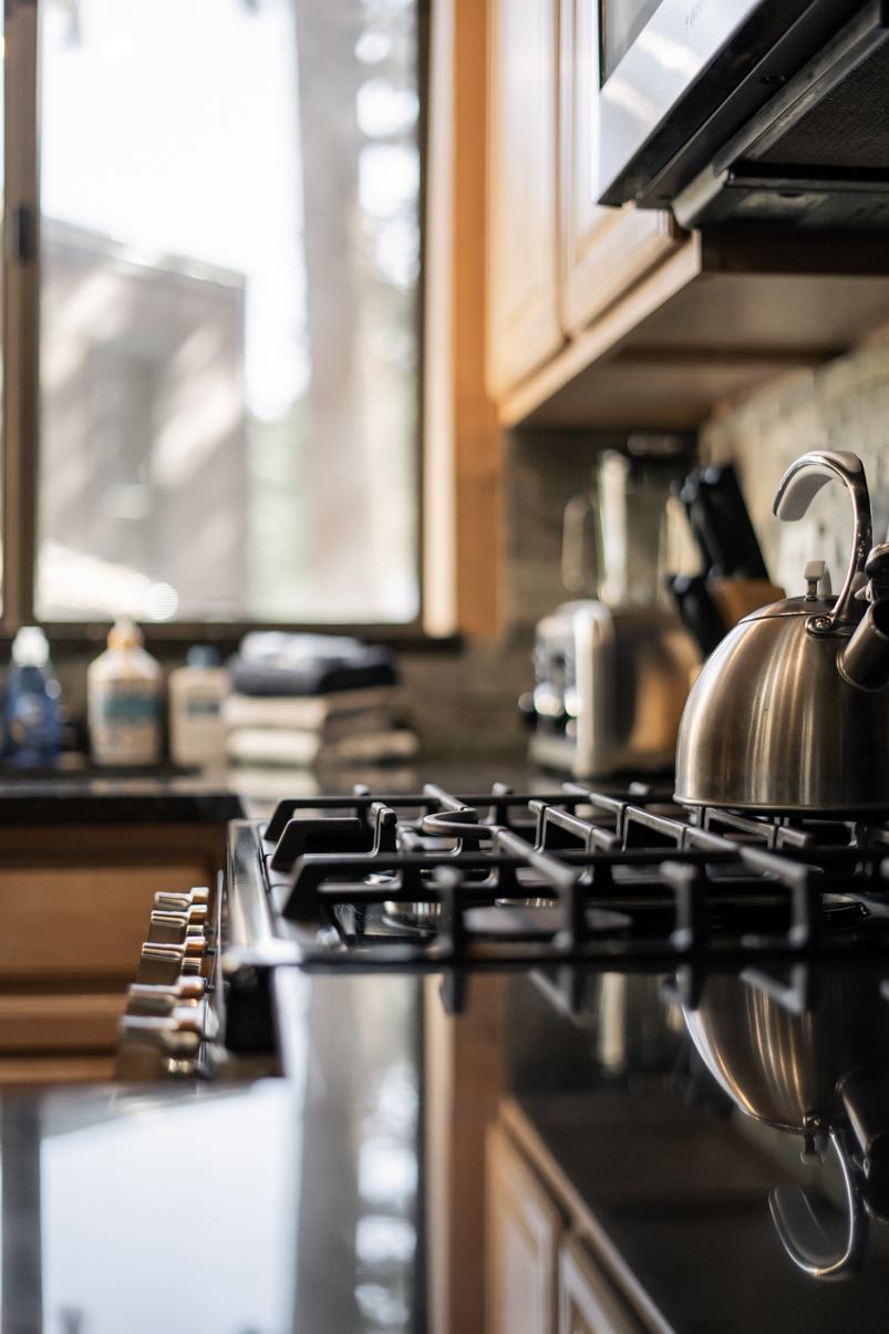 Cozy kitchen in a Truckee vacation rental featuring a modern stovetop and kettle near a sunlit window.