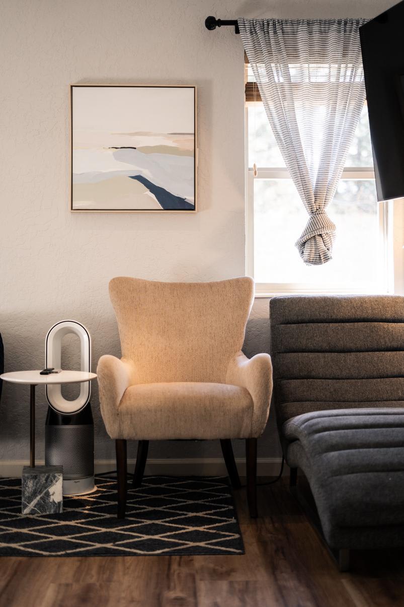 Cozy living area in a Truckee vacation rental with a beige armchair, abstract art, and natural light from a window.