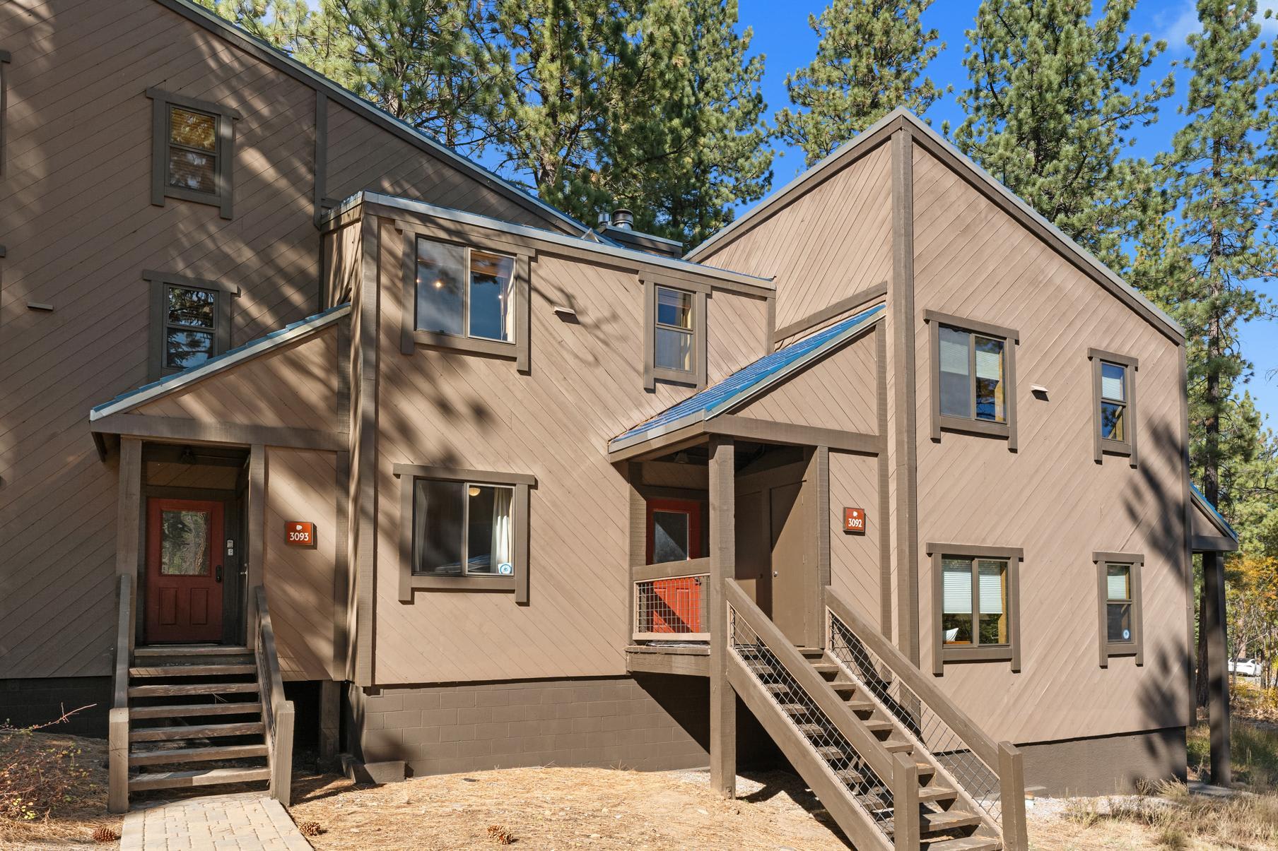 Wooden vacation rental home in Truckee, surrounded by tall trees under a clear blue sky.